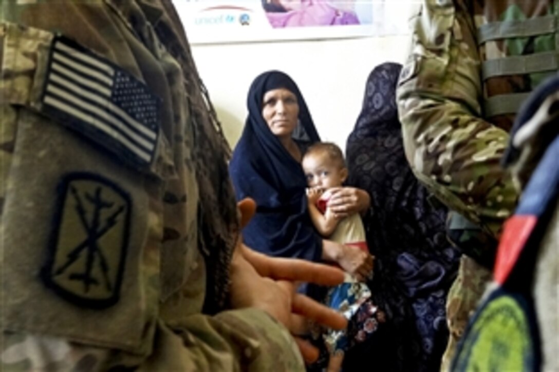 An Afghan mother and child watch as U.S. troops meet with the director of a nutritional center within the Farah Feeding Center in Farah City, Afghanistan, July 13, 2013. The troops are assigned to Provincial Reconstruction Team Farah, 2nd Battalion, 12th Field Artillery Security Force.