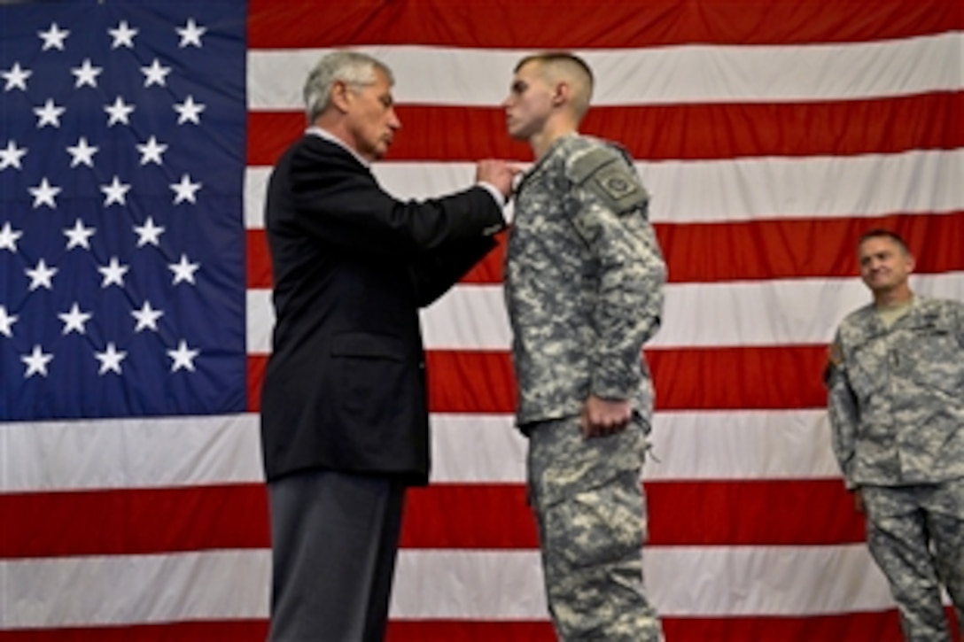 Defense Secretary Chuck Hagel pins a Purple Heart on Army Spc. Trevor Hoover during a troop event as he visits Fort Bragg, N.C., July 15, 2013. Hagel is on a three-day trip to visit bases to get feedback from troops on the effects of sequestration and furloughs.