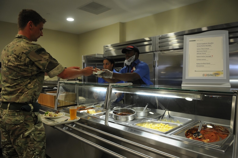 Sodexo worker Joseph Bandy passes a spaghetti dinner to 2nd Lt. George Stinton of the Royal Marines at the fusion station that’s a new feature of The Basic School’s chow hall that opened July 15, 2013, in Lopez Hall, replacing the old chow hall in O’Bannon Hall. 