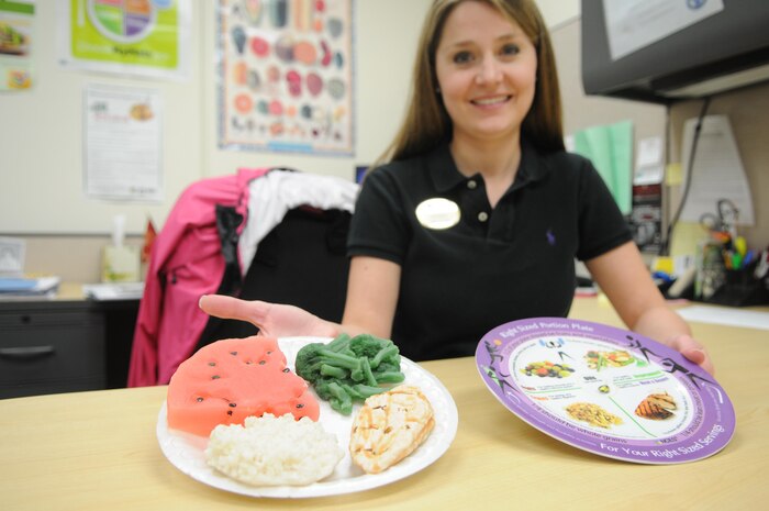 Semper Fit dietician Lauren King shows the plates and plastic portions that illustrate her “plate rule” for portioning food groups at mealtime. 