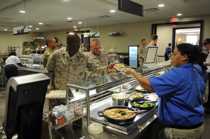 Sodexo worker Takeshia Juggins hands a meal to Sgt. Maj. Therester Cox of Marine Combat Training Battalion School of Infantry East, Camp Geiger, N.C., at the Charlston Market-themed food station that is new to The Basic School’s new chow hall now that it’s opened in the brand-new Lopez Hall. The new chow hall went into operation July 15, 2013. 