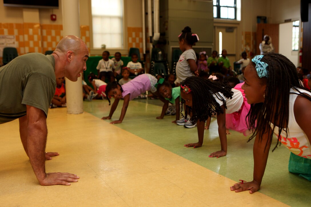 GySgt. Baltazar Zamora, staff secretary for Headquarters and Service battalion, 4th Marine Division, Marine Forces Reserve, and native of Los Angeles, demonstrates a series of exercises to students from St. Peter Claver Church school, July 11. Marines visited the students to perform techniques from the Marine Corps Martial Arts Program to build rapport with the local community. (U.S. Marine Corps photo by Cpl. John McCall)
