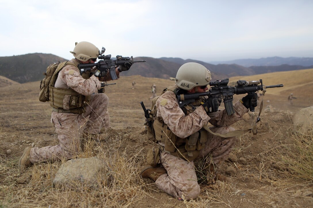 Sergeant Nate Kerr and Staff Sgt. Nicholas Busby, reconnaissance Marines serving with Alpha Company, 1st Reconnaissance Battalion, fire at enemy targets during a raid exercise here, July 10, 2013. Kerr, 25, from Dana Point, Calif., Busby, 27, from Belleville, Ill., and their team maneuvered around a hill to flank the enemy.