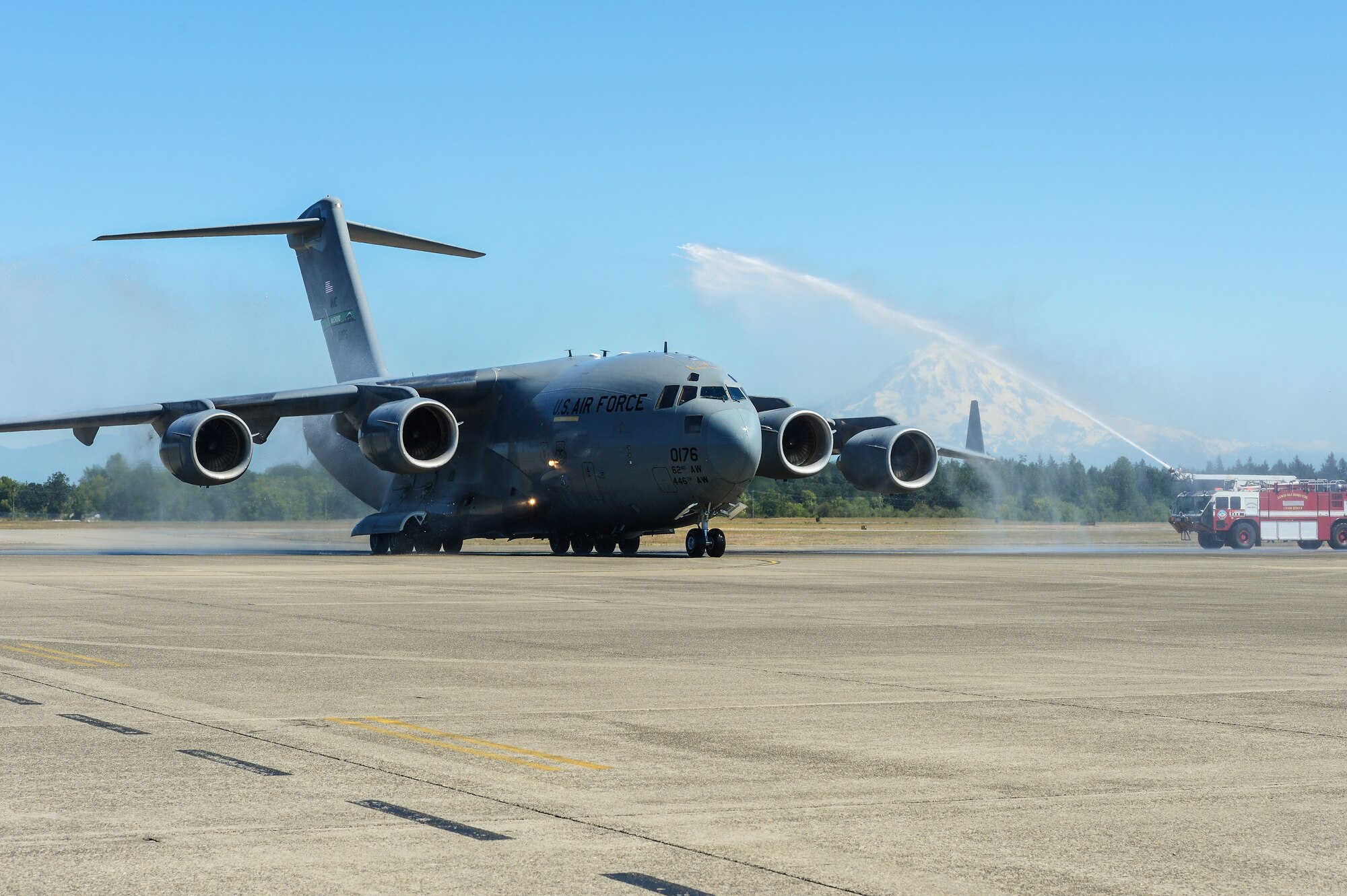 A C-17 Globemaster III is showered by fire trucks as it taxies back after a training flight July 15, 2013, at Joint Base Lewis-McChord, Wash. The flight, commanded by Col. Wyn Elder, 62nd Airlift Wing commander, was Elder's final flight as the wing commander. (U.S. Air Force Photo/Tech Sgt. Sean Tobin)