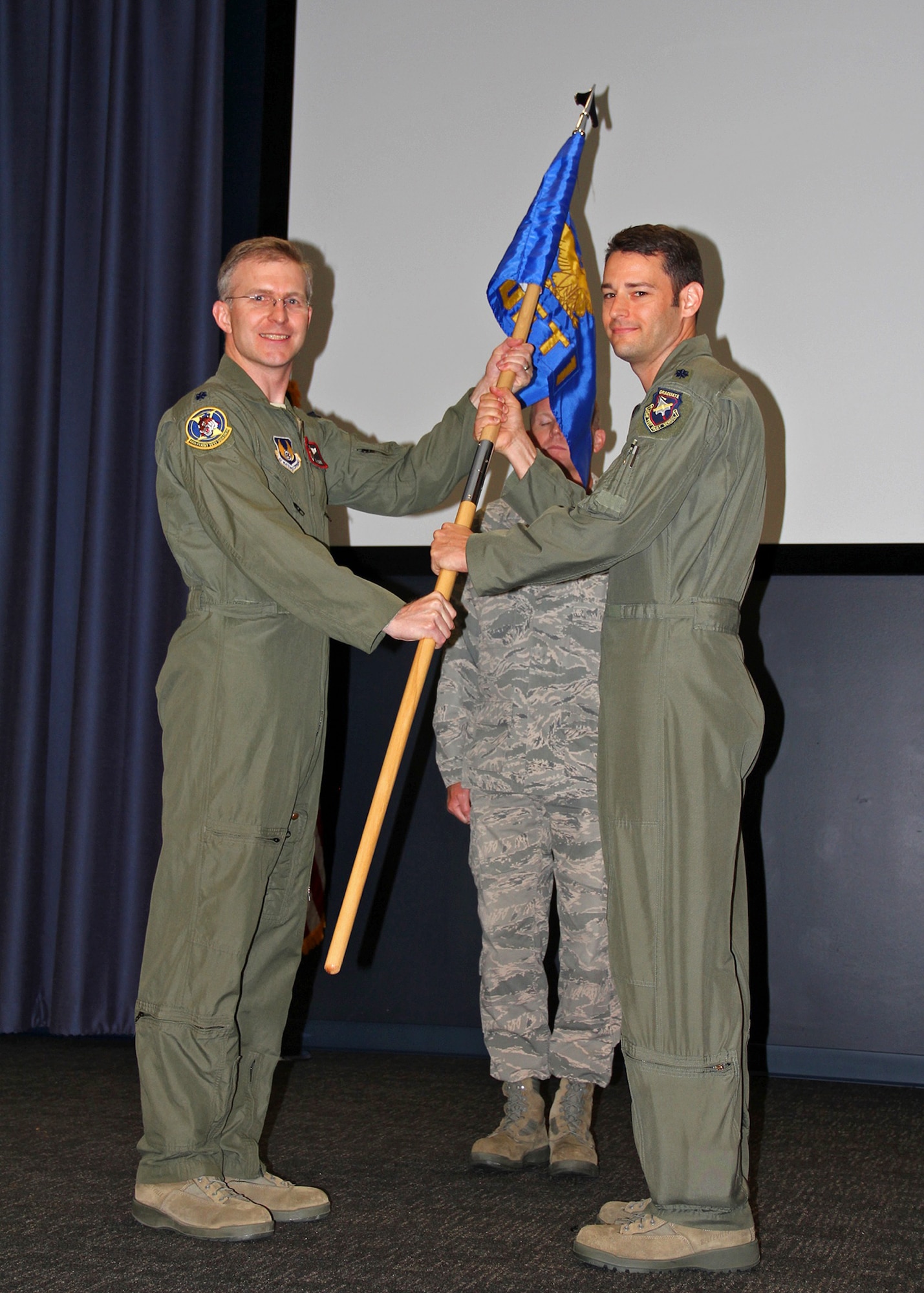 Lt. Col. Charles Cain (left), 418th Flight Test Squadron commander, passes the 418th FLTS, Detachment 1 guideon to Lt. Col. James Quashnock, charging him with command during a ceremony in Seattle, Wash. on July 11, 2013. The 418th FLTS, Det. 1 will be the responsible test organization for developmental test on the KC-46. (U.S. Air Force photo by Maj. Donevan Rein)