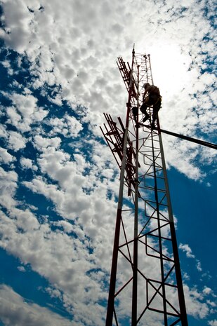 U.S. Air Force Staff Sgt. Corie Brassfield, 99th Communications Squadron airfield systems technician, climbs a signal tower on the flightline to change a light July 15, 2013, at Nellis Air Force Base, Nev. The light on the tower gives pilots a reference to where the air traffic control tower is. (U.S. Air Force photo by Senior Airman Daniel Hughes)