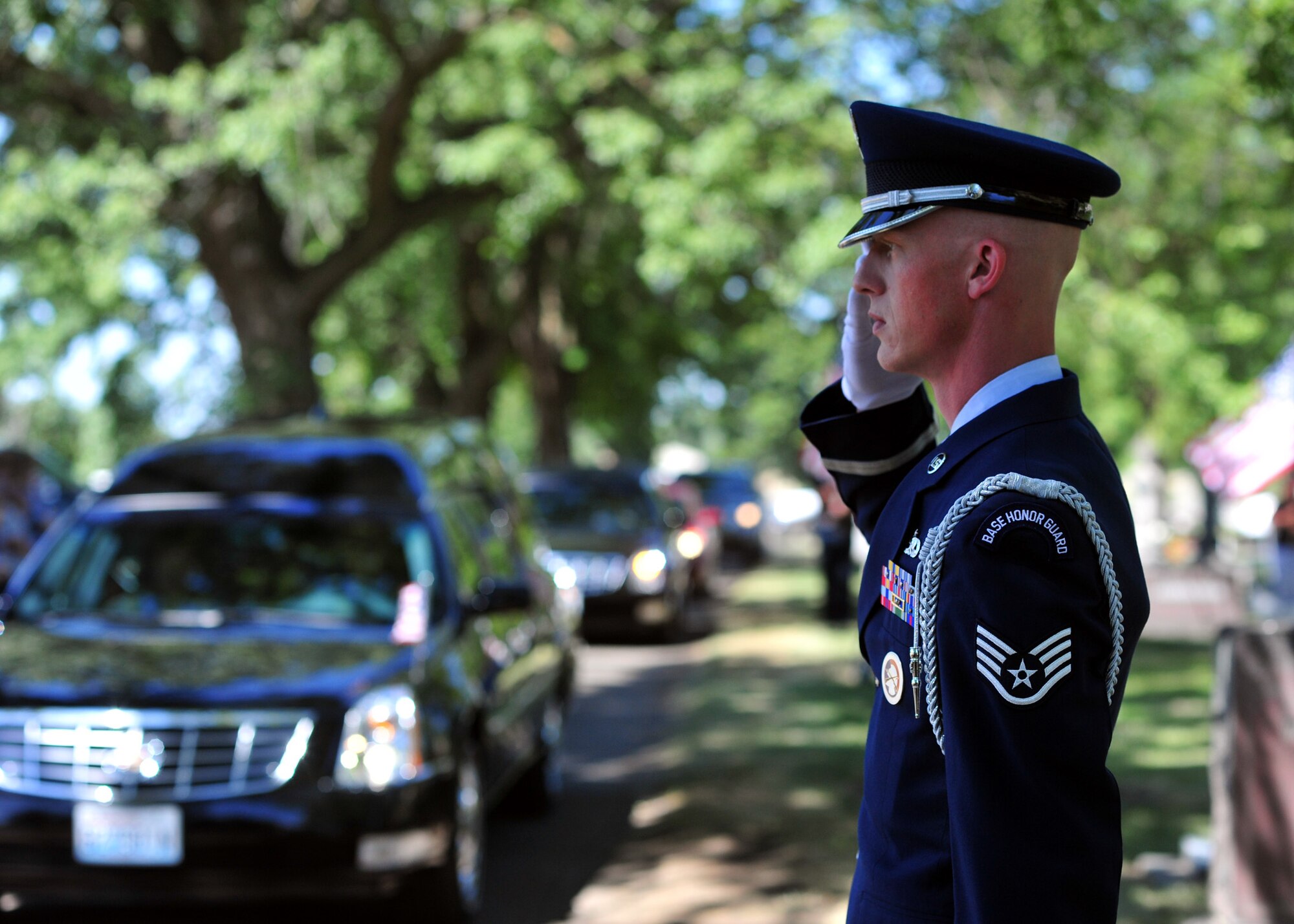 Staff Sgt. Terrill Castor, Fairchild Air Force Base honor guard NCO in charge, salutes as Maj. Larry Hanley is driven by in the hearse during his funeral service in Walla Walla, Wash., July 13, 2013. Honor guard members were in attendance to present the colors and perform a rifle salute as well. (U.S. Air Force photo by Senior Airman Taylor Curry/Released)