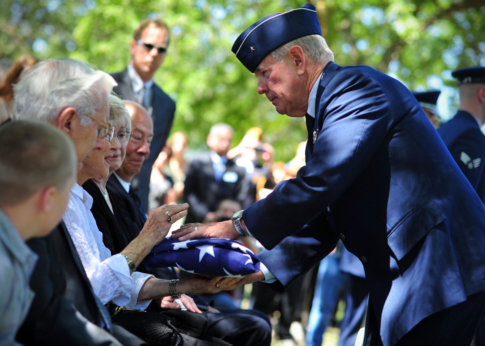 (Retired) Brig. Gen. James McDevitt hands off the American Flag that was draped over Maj. Larry Hanley’s casket, to JoAnn Aliverti, Hanley’s sister, during Hanley’s funeral service in Walla Walla, Wash., July 13, 2013. (U.S. Air Force photo by Senior Airman Taylor Curry/Released)