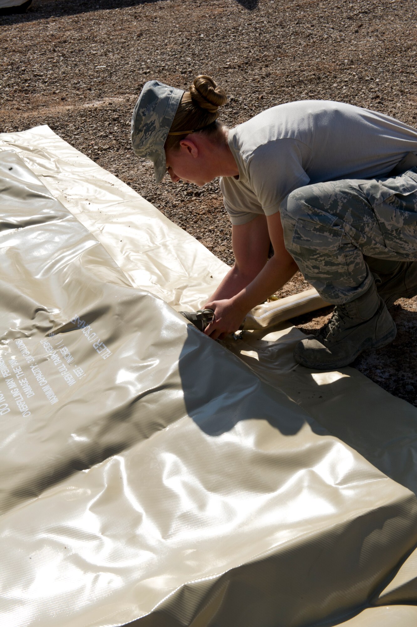 Airman 1st Class Melissa Holmberg, 49th Materiel Maintenance Squadron utilities shop journeyman, adjusts a water line on a storage bladder during a Basic Expeditionary Airfield Resources Base five-day training exercise at Holloman Air Force Base, N.M., July 10. The bladder will supply water to a deployed shower facility. (U.S. Air Force photo by Senior Airman Kasey Close/Released)