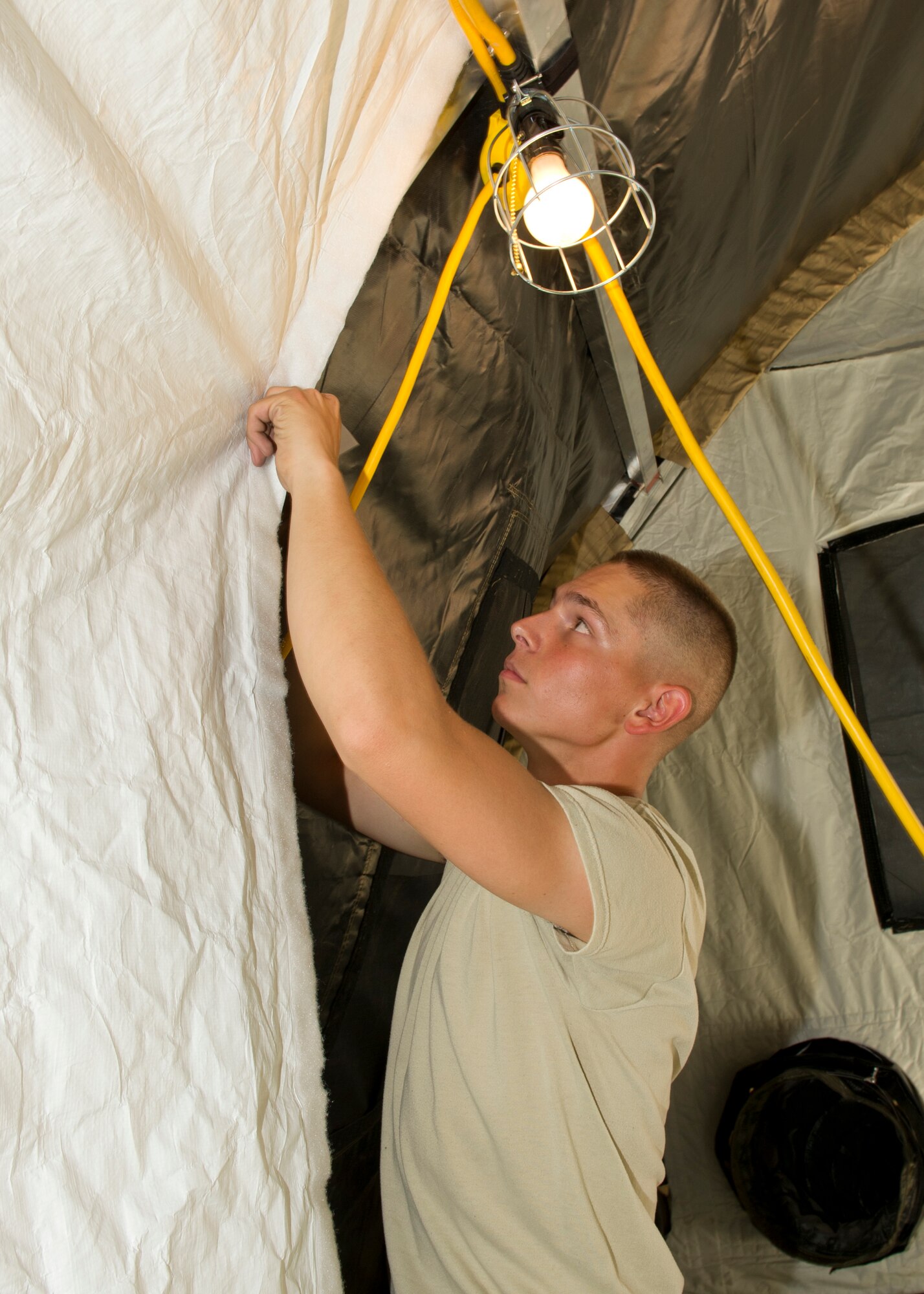 Airman 1st Class Bryce Bigboy, 49th Materiel Maintenance Squadron structural apprentice, attaches a liner to a small shelter tent during a Basic Expeditionary Airfield Resources Base five-day training exercise at Holloman Air Force Base, N.M., July 10. The liner adds an additional layer to protect occupants from hot or cold weather conditions. (U.S. Air Force photo by Senior Airman Kasey Close/Released)