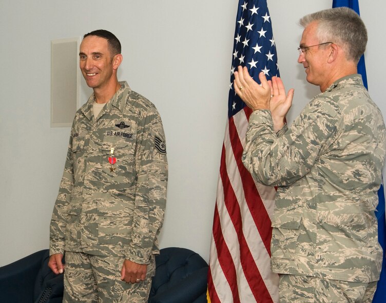 Gen. Paul Selva, Air Mobility Command commander, applauds Tech. Sgt. Doug Beish, 436th Operations Support Squadron Air Crew training C-5 Globemaster III loadmaster training, after receiving the Bronze Star Medal July 10, 2013, at Dover Air Force Base, Del. Beish was deployed to Iraq and assigned to Air Mobility Director U.S. Special Operations Command as a liaison for special operations commands and conventional airlift commands. (U.S. Air Force photo/Senior Airmen Jared Duhon)