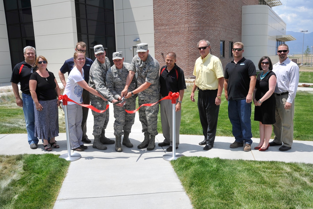 PETERSON AIR FORCE BASE, Colo. – (Left to right) Lt. Col. Mark Guerber, 16th Space Control Squadron commander, Col. Chris Crawford, 21st Space Wing commander, and Lt. Col. Dean Sniegowski, 380th SPCS director of operations, along with members from Bryan Construction, the contractor which built the building, cut a ribbon June 28 ceremoniously opening building 2027. Building 2027 is the new home to the 16th SPCS and its Reserve Associate Unit, the 380th SPCS. (U.S. Air Force photo/Robb Lingley)