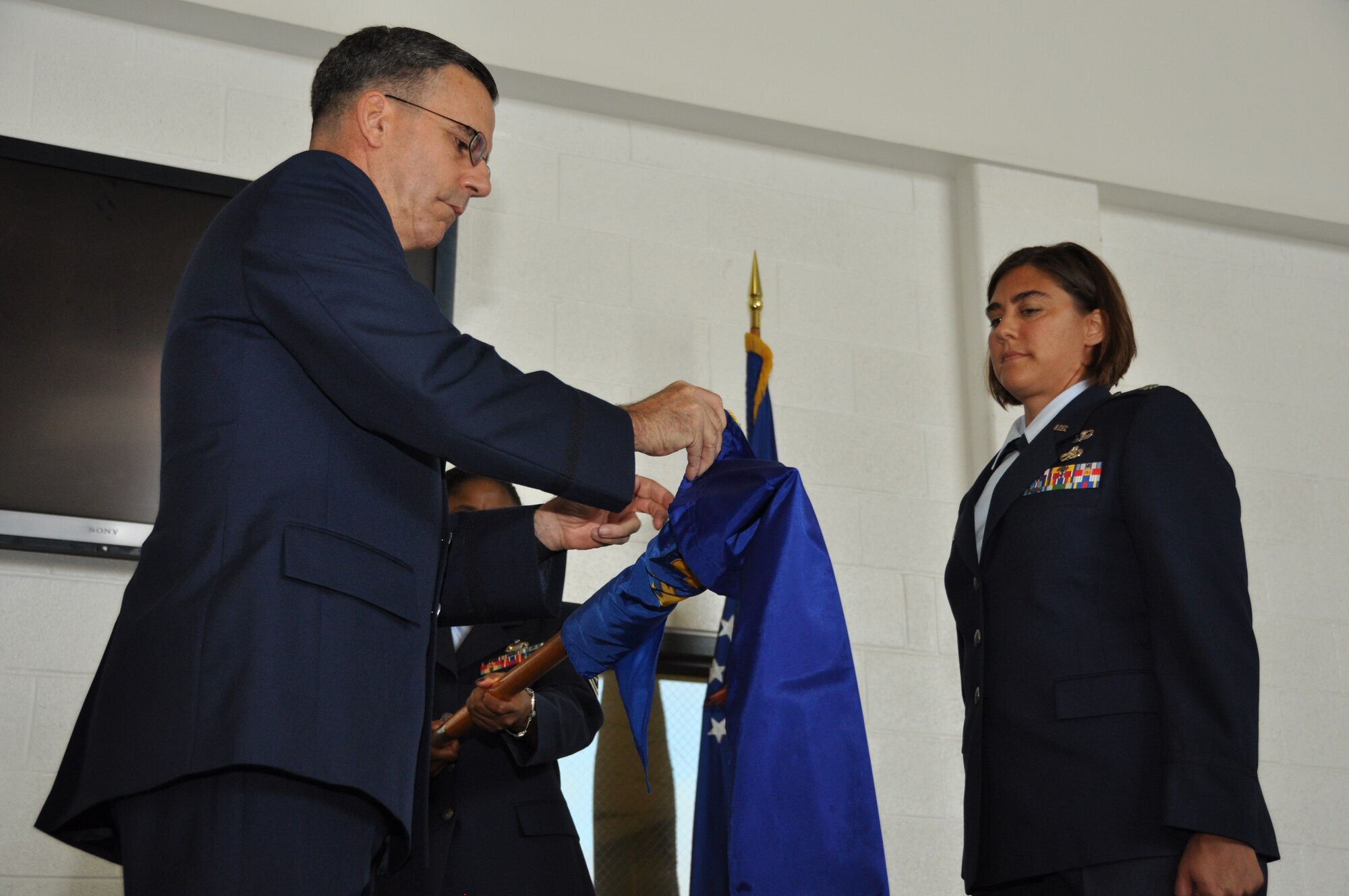 U.S. Air Force Col. Donald Robison, 459th Maintenance Group commander, puts a sleeve on the retired flag and guidon for the 459th Maintenance Operations Flight with Air Force Lt. Col. Erica Foster, 459 MOF commander, in an inactivation ceremony at Joint Base Andrews, Md., July 13, 2013. The 459 MOF was inactivated due to Air Force budgetary decisions and reorganization within the Air Force. (U.S. Air Force photo by Staff Sgt. Brent A. Skeen)