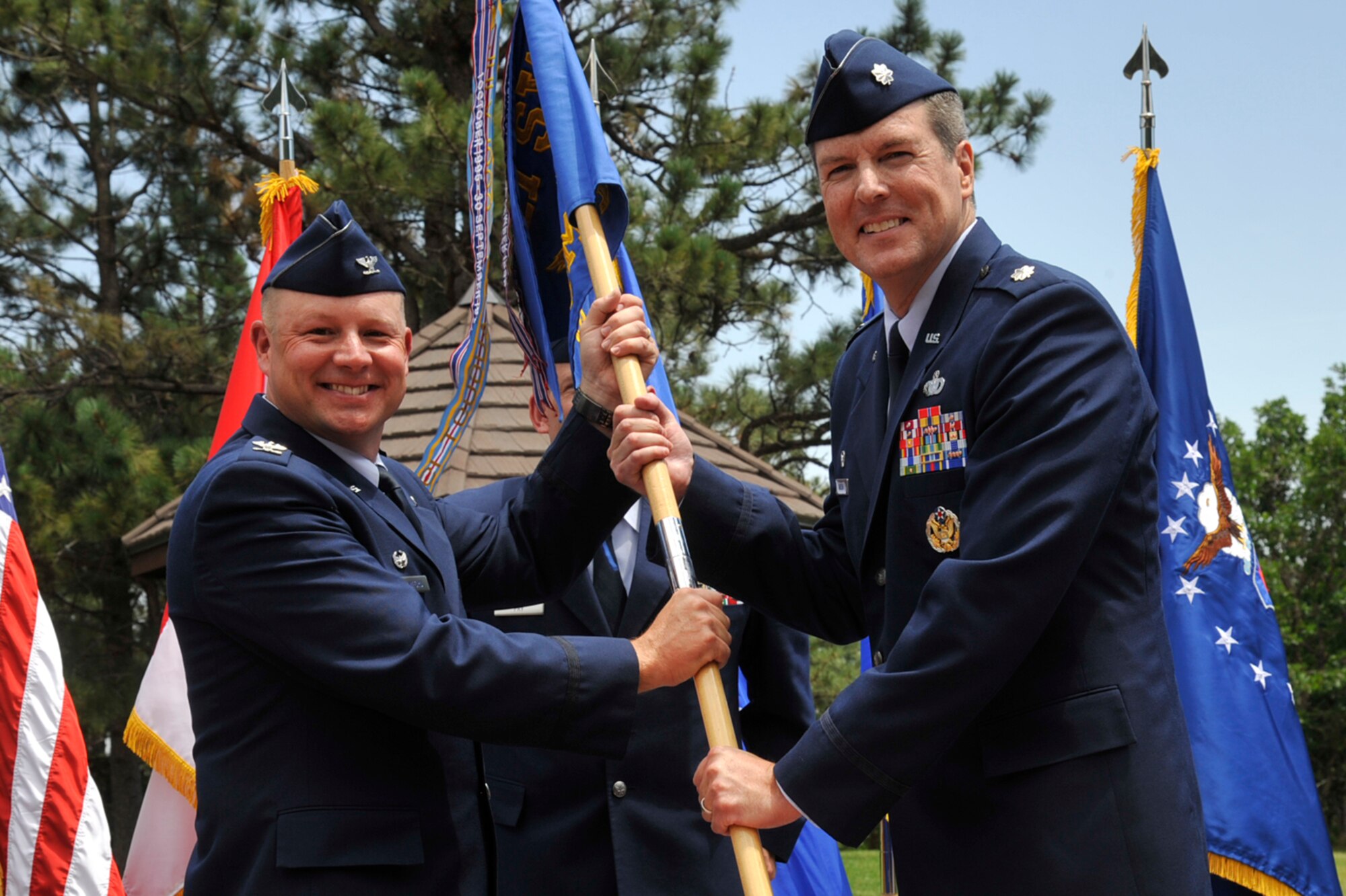 CHEYENNE MOUNTAIN AIR FORCE STATION, Colo. – Col. Chris Crawford (left), 21st Space Wing commander, passes the 721st Mission Support Group guidon to Lt. Col. Travis Harsha July 11 at the Cheyenne Mountain AFS Minuteman Park. The 721st MSG, located at Cheyenne Mountain Air Force Station, operates, maintains, secures, sustains, mobilizes, tests, and controls the worldwide warning and surveillance system for North America, normally referred to as the Integrated Tactical Warning and Attack Assessment (ITW/AA) weapon system. Harsha is the CMAFS installation commander and 721st MSG commander. He takes over from outgoing commander Col. Joseph Turk who is retiring. (U.S. Air Force photo/Robb Lingley)
