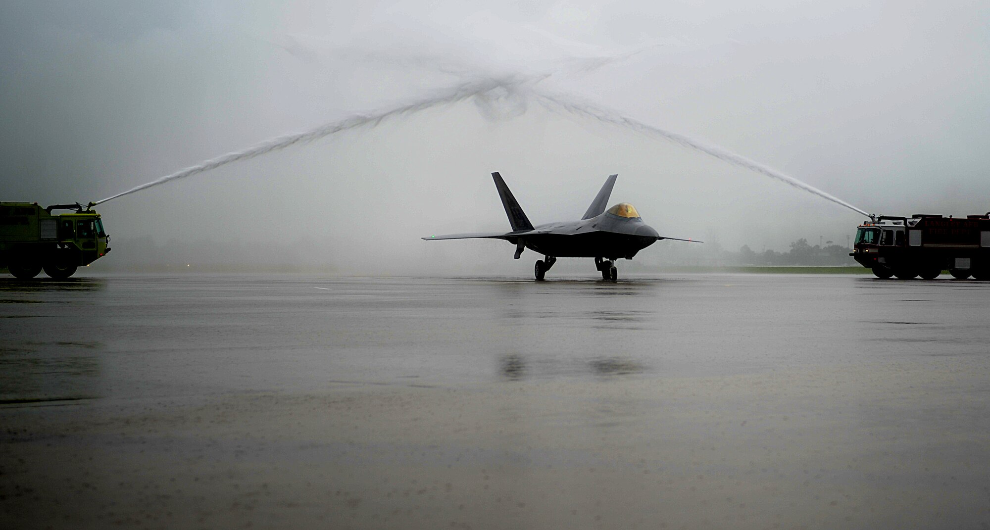 Col Kevin J. Robbins, 1st Fighter Wing commander, maneuvers an F-22 Raptor between two fire engines after his “fini flight” at Langley Air Force Base, Va., July 12, 2013. Following the flight, Robbins was greeted by his family, friends and Airmen of the 1st FW. (U.S. Air Force photo by Airman 1st Class Kimberly Nagle/Released)