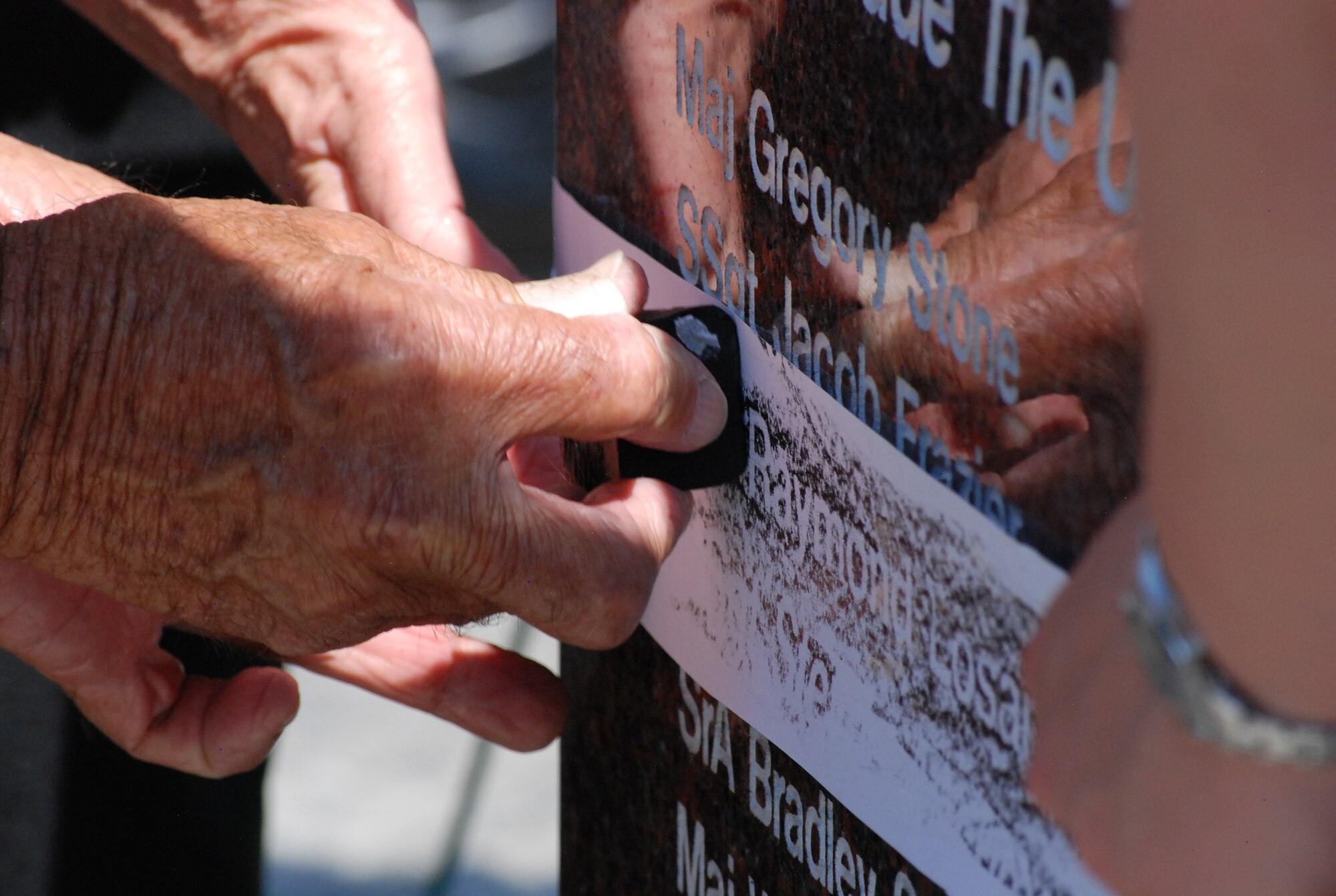 COLORADO SPRINGS, Colo. – Family members of the fallen Airmen rub wax onto strips of paper after the ceremony, creating impressions of their loved ones’ names to be taken home with them. “Stone rubbing” is a tradition that was made popular in the early 1980s by visitor to the Vietnam Veterans Memorial in Washington, D.C., and has carried on since. (U.S. Air Force photo/Michael Golembesky)