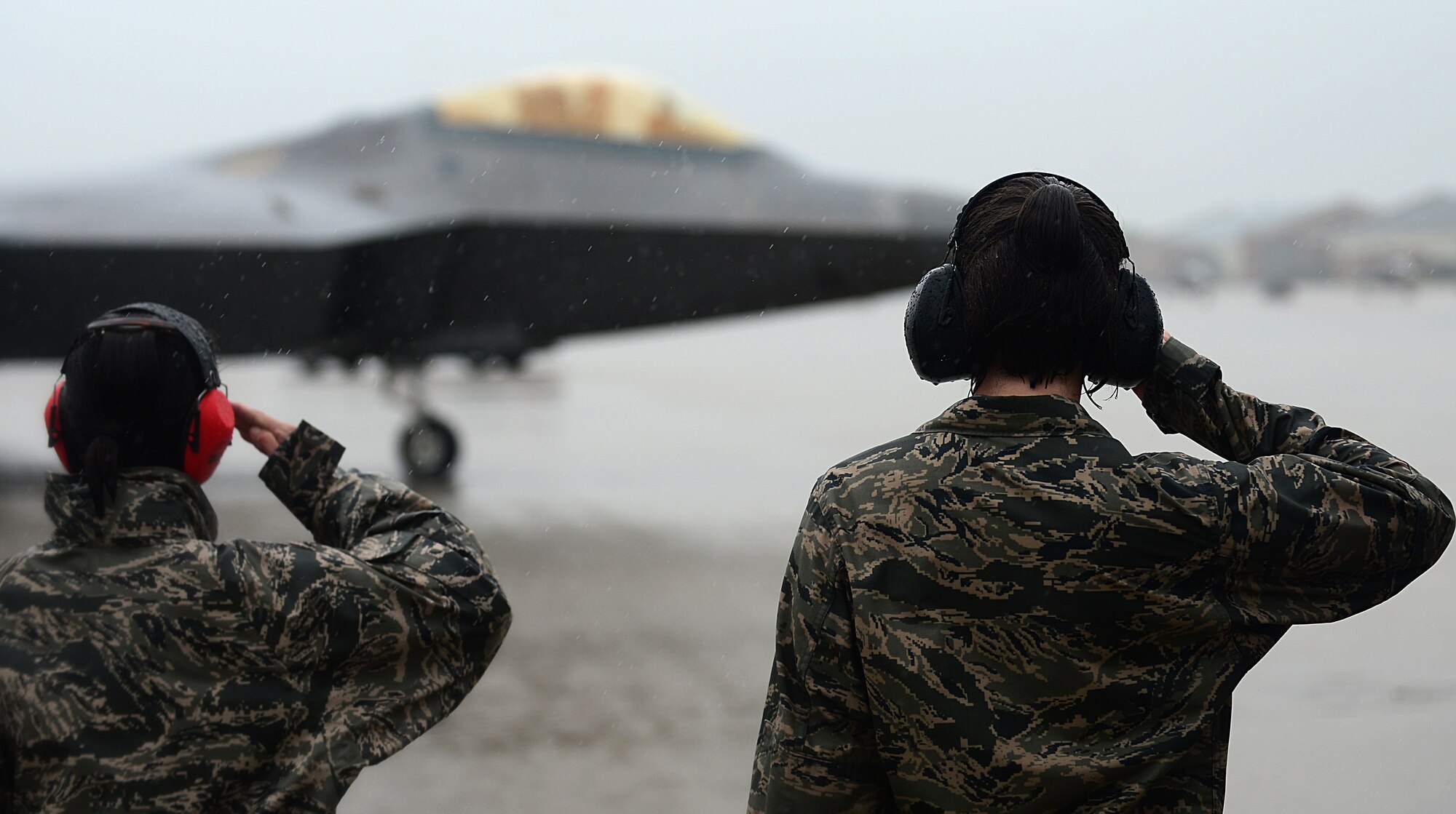 Two U.S. Air Force Airmen salute as Col. Kevin J. Robbins, 1st Fighter Wing commander, returns from his “fini flight” at Langley Air Force Base, Va., July 12, 2013. The “fini flight” tradition was first officially noted in Vietnam, when the aircrew commemorated the completion of 100 missions. (U.S. Air Force photo by Senior Airman Kayla Newman/Released)