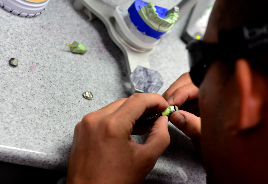 U.S. Air Force Senior Airman Jordan Barragan, 633rd Dental Squadron laboratory technician, inspects a crown at the dental clinic at Langley Air Force Base, Va., July 10, 2013. The lab makes crowns, mouth guards and retainers for Langley Airmen. (U.S. Air Force photo by Airman 1st Class R. Alex Durbin/Released)