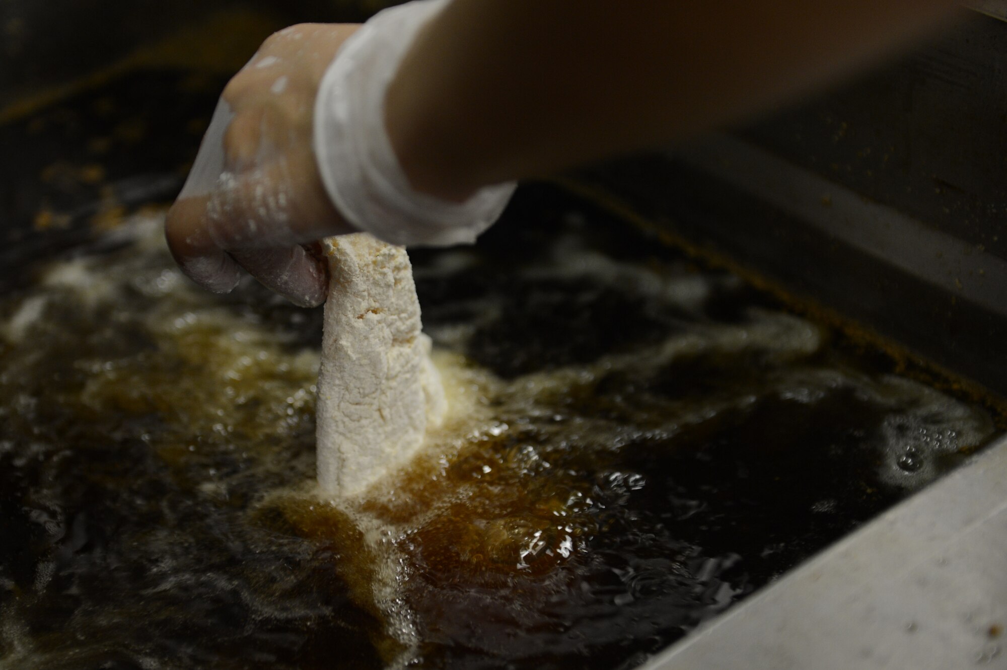 Airman 1st Class Mahoghamo Crews, 20th Force Support Squadron food services apprentice, fries catfish at the Chief Master Sgt. Emerson Williams Dining Facility at Shaw Air Force Base, July 11, 2013. Dining facility menus are planned and rotated on a 14-day cycle. (U.S. Air Force photos by Airman 1st Class Krystal M. Jeffers/Released)