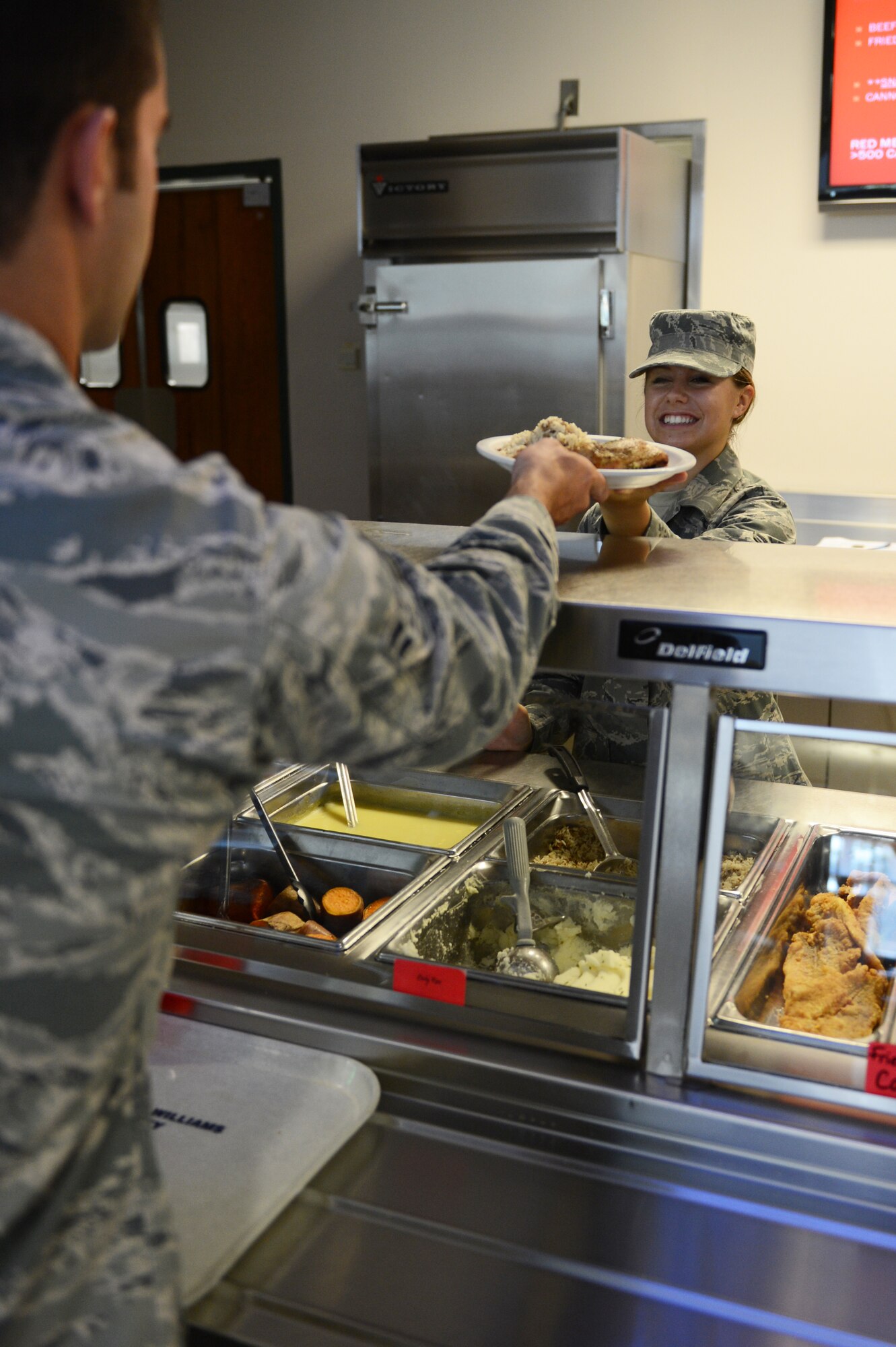Airman 1st Class Michaela Boles, 20th Force Support Squadron food services apprentice, serves food during lunch at the Chief Master Sgt. Emerson Williams Dining Facility at Shaw Air Force Base, July 11, 2013. Meal preparation begins two hours prior to it being served; the staff prepares enough food for approximately 100 people. The staff continues to cook food during each meal to ensure the food is served hot and freshly. (U.S. Air Force photos by Airman 1st Class Krystal M. Jeffers/Released)