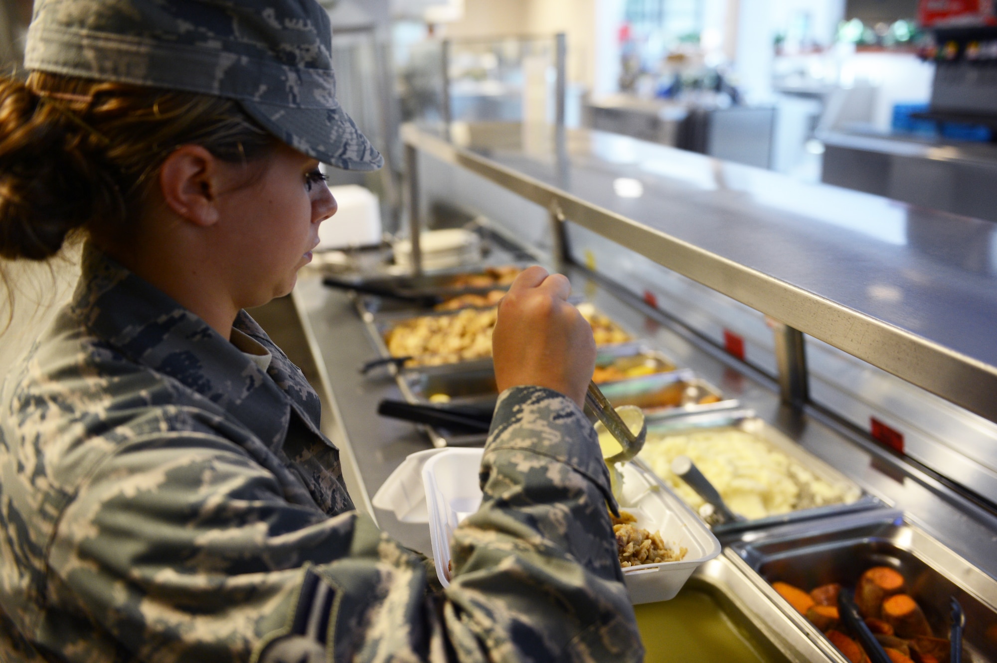 Airman 1st Class Michaela Boles, 20th Force Support Squadron food services apprentice, serves food during lunch at the Chief Master Sgt. Emerson Williams Dining Facility at Shaw Air Force Base, July 11, 2013. The dining facility staff works around-the-clock every day of the year to provide service members daily meals. (U.S. Air Force photos by Airman 1st Class Krystal M. Jeffers/Released)