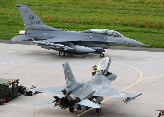 LASK AIR BASE, Poland -- A U.S. Air Force F-16 Fighting Falcon fighter aircraft pilot acknowledges a wave from a Polish air force maintainer July 16, 2013. The F-16, from Aviano Air Base, Italy, taxied toward the arming station before beginning the day's training session. (U.S. Air Force photo by Staff Sgt. Daryl Knee/Released)