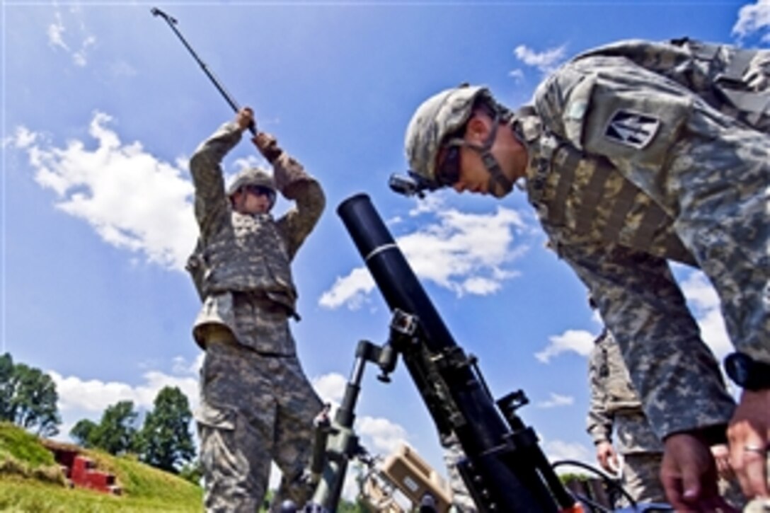 Army Spc. Robert Davis cleans a 120mm mortar tube between fire missions on Camp Atterbury, Ind., July 13, 2013. Davis is assigned to the Indiana National Guard's Headquarters Company, 1st Battalion, 293rd Infantry Regiment.