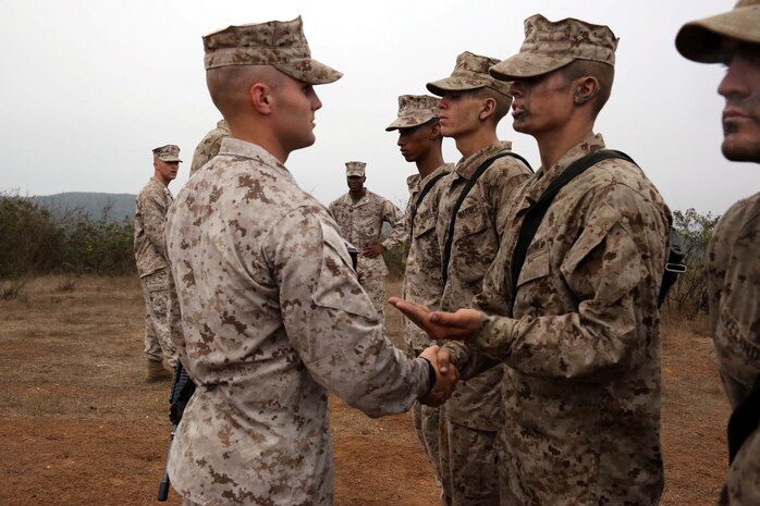 Sgt. Sean A. Legaard, senior drill instructor, Company L, 3rd Recruit Training battalion, gives a new Marine an emblem, a hand shake and a few words of encouragement at Edson Range aboard Marine Corps Base Camp Pendleton Calif., July 11.   