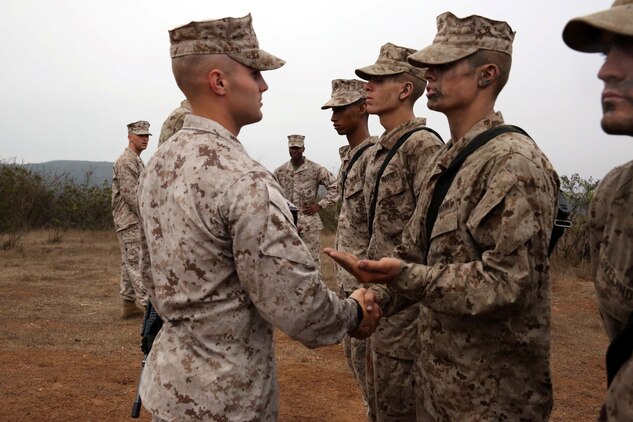 Sgt. Sean A. Legaard, senior drill instructor, Company L, 3rd Recruit Training battalion, gives a new Marine an emblem, a hand shake and a few words of encouragement at Edson Range aboard Marine Corps Base Camp Pendleton Calif., July 11.   