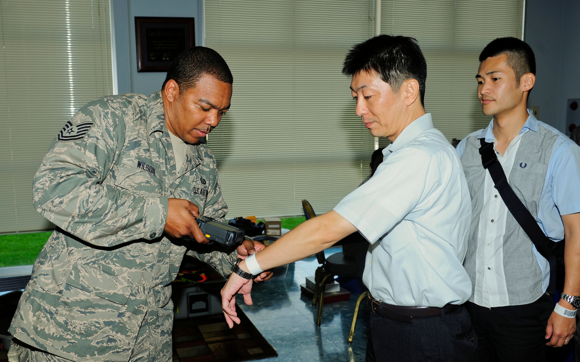 Tech. Sgt. Charles Wilson, 374th Force Support Squadron, scans the wristbands of Non-combative Evacuation Operation scenario role players at the Taiyo Community Center during the Operational Readiness Exercise on Yokota Air Base, Japan, July 15, 2013. The NEO scenario was one of many practiced throughout the duration of the ORE.  (U.S. Air Force photo by Senior Airman Michael Washburn/released)