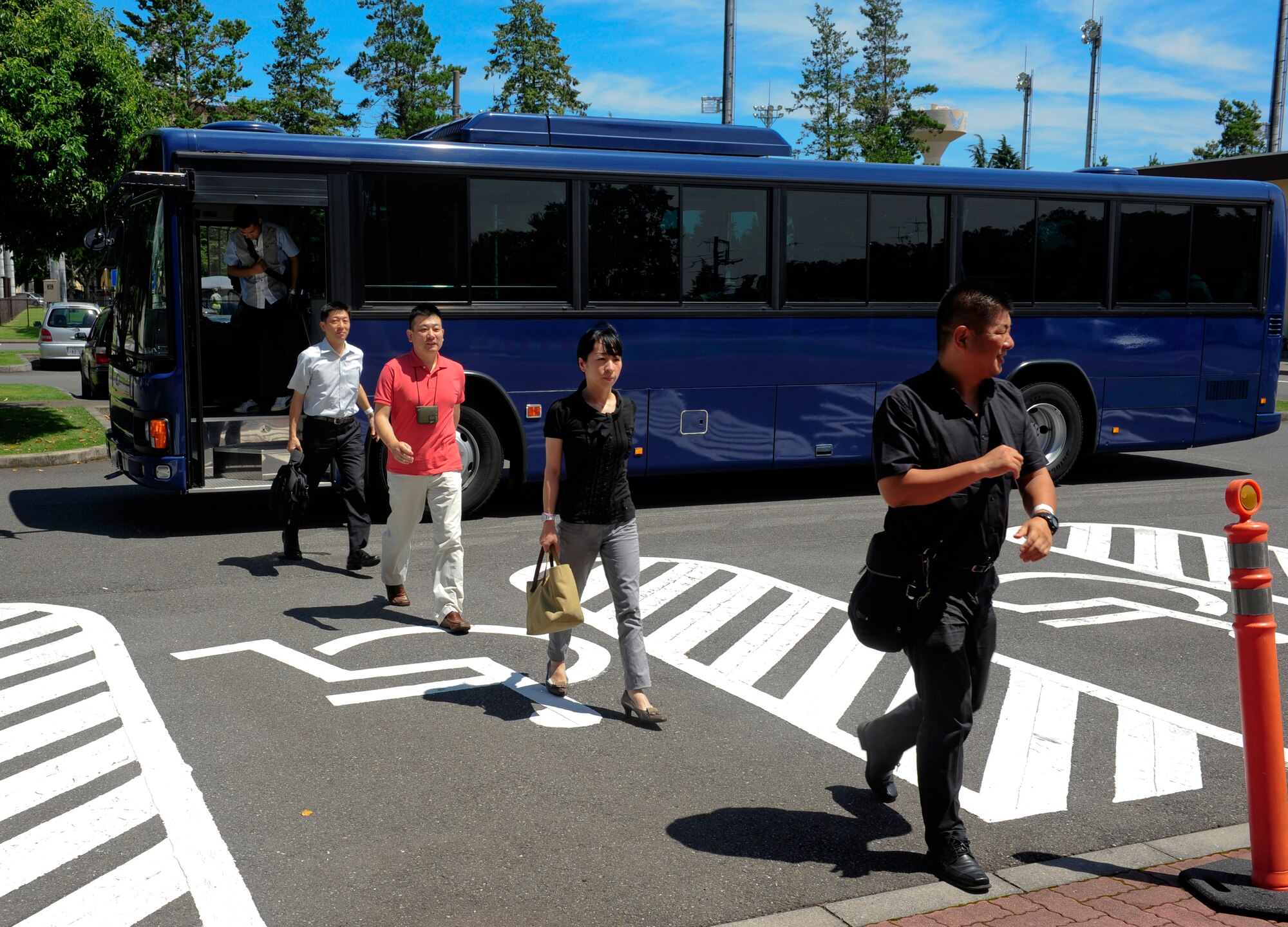 Role players dismount a bus at the Taiyo Community Center during a simulated Non-combative Evacuation Operation during the Operational Readiness Exercise on Yokota Air Base, Japan, July 15, 2013. The bi-lateral role players were both Air Force Airmen and Japan Air Self-Defense Force members to help add realism to the scenario.  (U.S. Air Force photo by Senior Airman Michael Washburn/released)