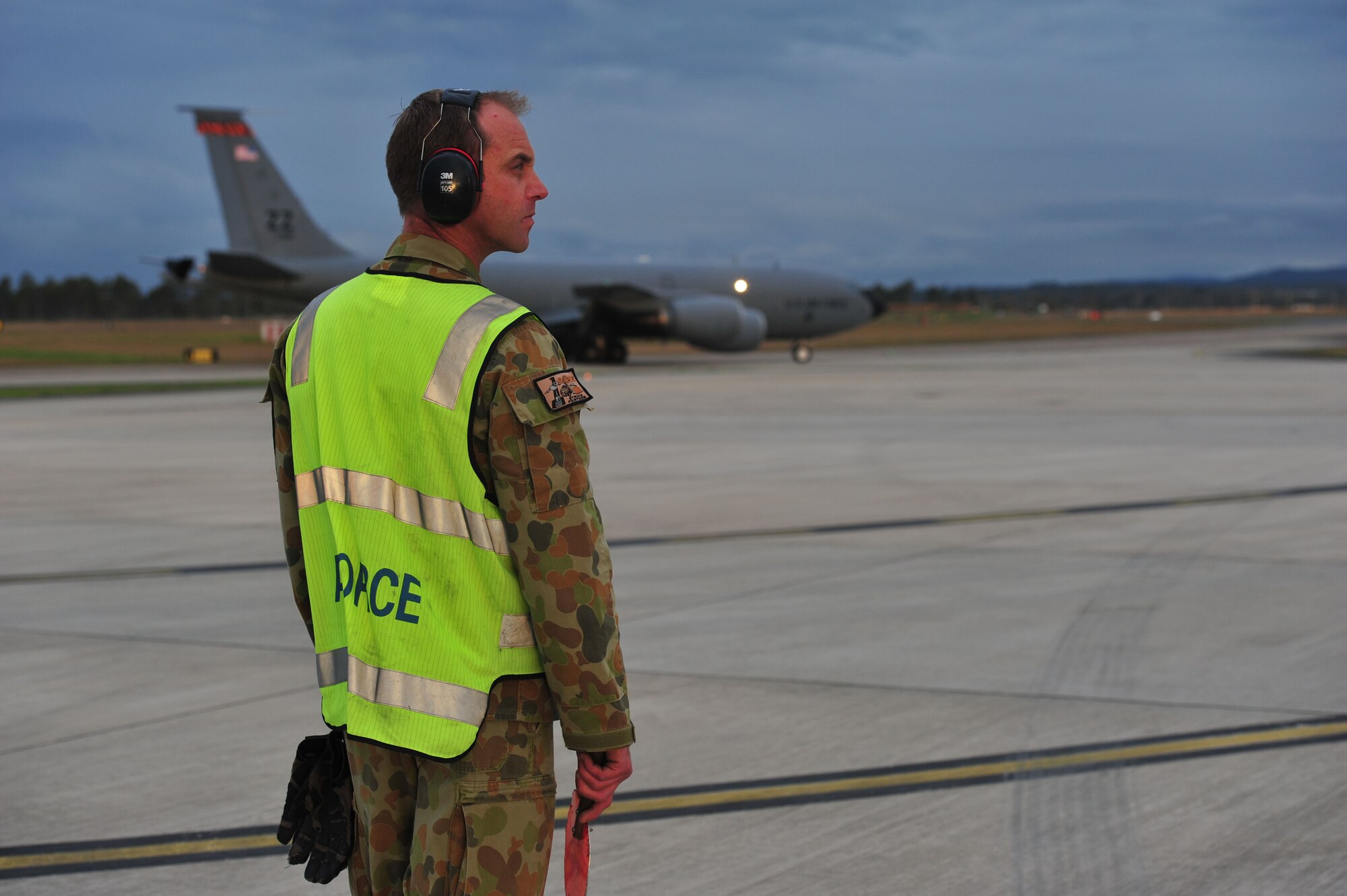 Royal Australian Air Force Leading Aircraftman Damien Deering, assigned to the No. 1 Airfield Operations Support Squadron, prepares to marshall a U.S. Air Force KC-135 Stratotanker from Kadena Air Base, Japan, to its parking space at Royal Australian Air Force Base Amberley, Australia, July 15, 2013. Two KC-135s arrived to provide aerial refueling during Talisman Saber 2013, a biennial training activity aimed at improving Australian Defence Force and U.S. combat readiness and interoperability as a combined joint task force. (U.S. Air Force photo by Staff Sgt. Rachelle Coleman/Released)