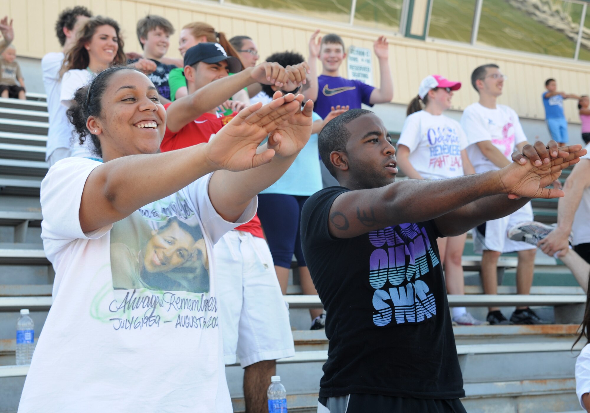 Senior Airman Roslyn Longmire, 384th Air Refueling Squadron boom operator, and Airman 1st Class Matthew Hammond, 22nd Contracting Squadron contracting administrator, participate in a group warm up at the Relay for Life of Derby July 12, 2013, Derby, Kan. Throughout the 12 hour event, team members take turns walking around the track to help raise awareness and funds toward fighting cancer. (U.S. Air Force photo/Airman 1st Class John Linzmeier)