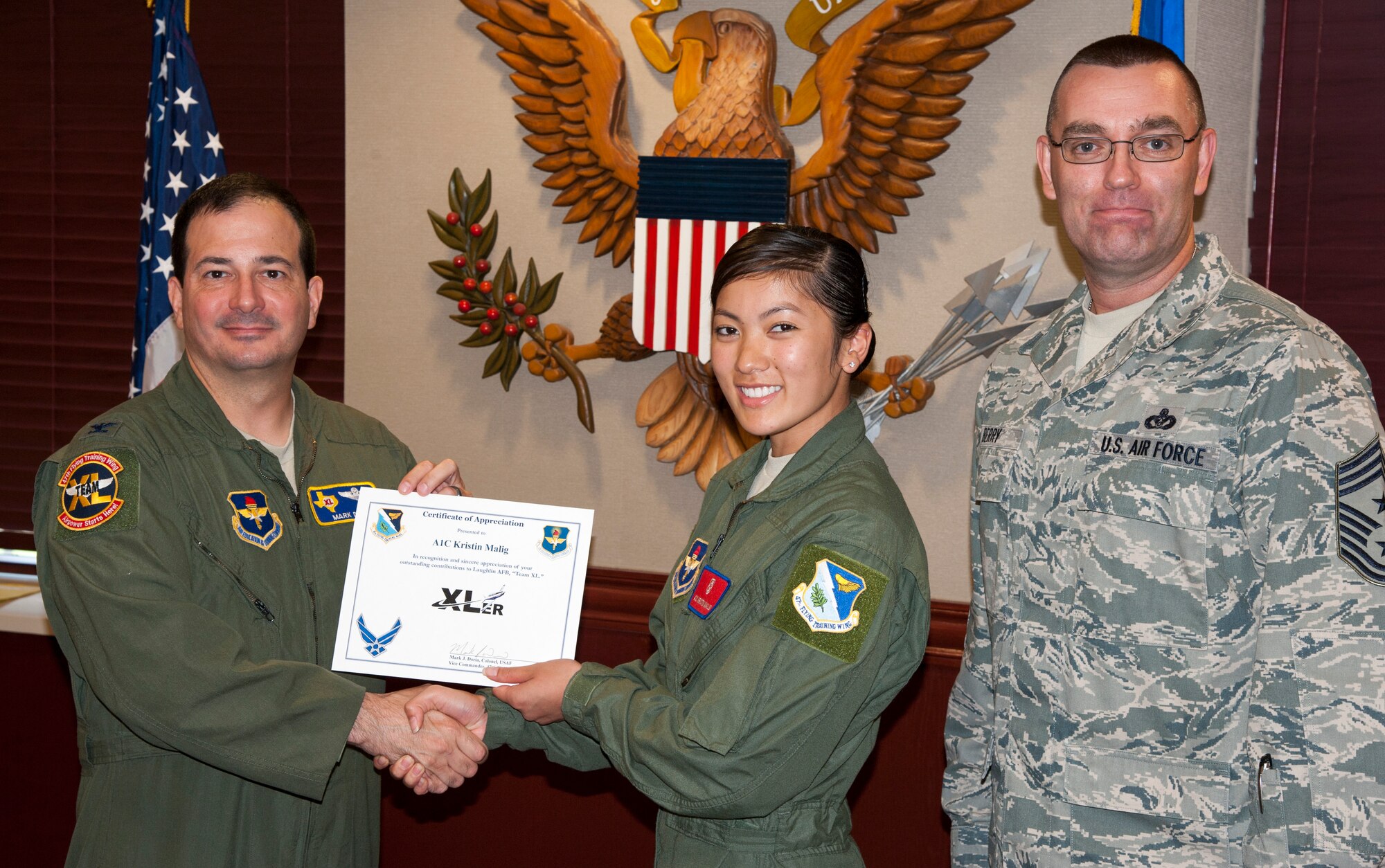 Airman 1st Class Kristin Malig, 47th Medical Operations Support Squadron Aerospace and Operational Physiology technician, poses with Col. Mark Doria, 47th Flying Training Wing vice commander, and Chief Master Sgt. Garry Berry, 47th FTW command chief, after being presented the XLer of the week award here July 2, 2013. The XLer is a weekly award chosen by wing leadership and given to those who consistently make outstanding contributions to Laughlin and their unit. (U.S. Air Force photo/Joel Langton)

