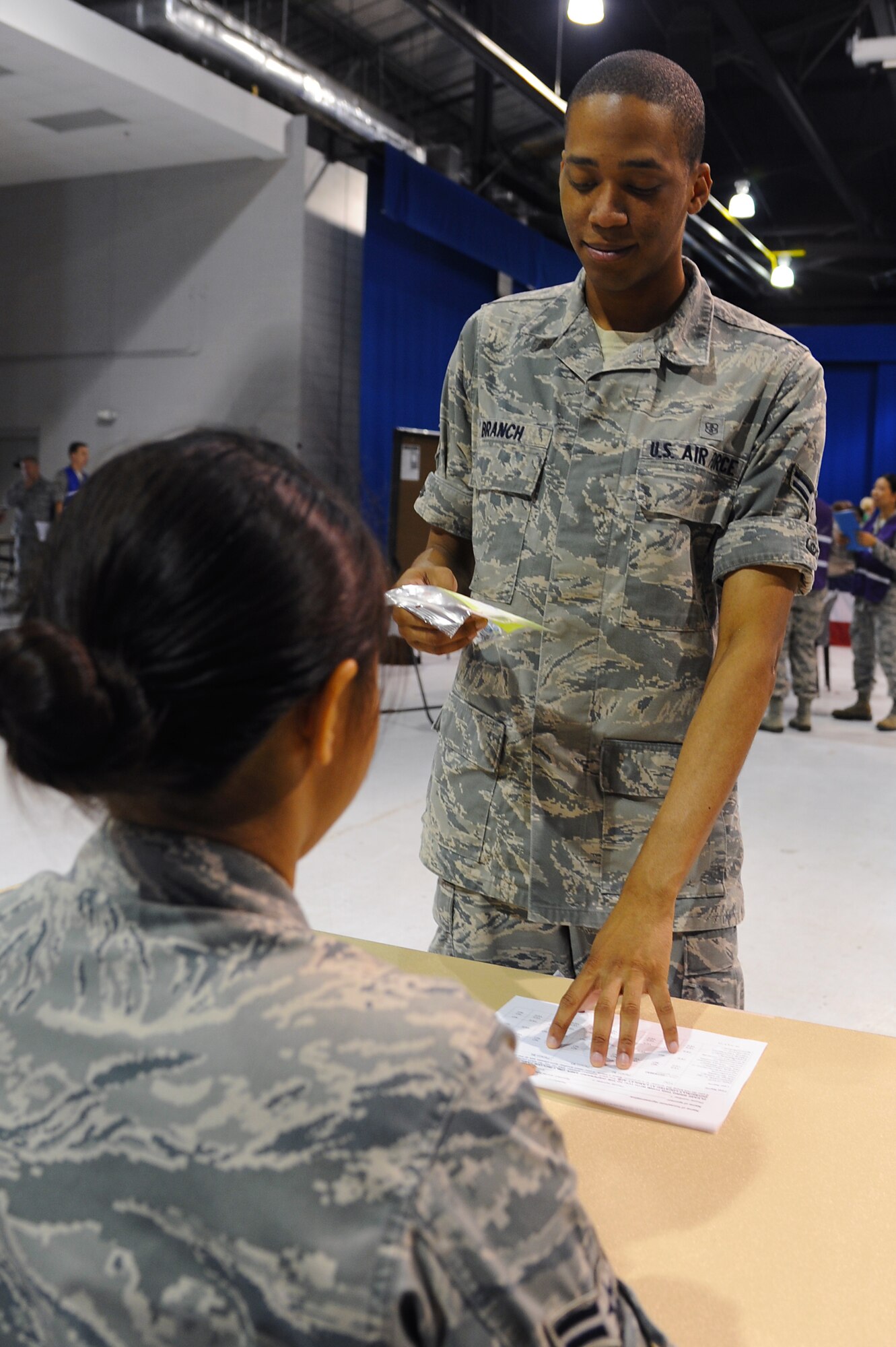 U.S. Air Force Airman 1st Class Michael Branch, 633rd Medical Group pharmacy technician, simulates receiving medication from Airman 1st Class Jessa Gatchalian, 633rd MDG pharmacy technician, during a Major Accident Response Exercise at Langley Air Force Base, Va., July 16, 2013. The exercise tested the 633rd MDG’s ability to activate a point of distribution and dispense prophylaxis. (U.S. Air Force photo by Airman 1st Class Victoria H. Taylor/Released)