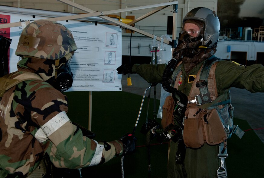 An Airman from the 28th Operations Support Squadron decontaminates a pilot assigned to the 37th Bomb Squadron in the Pride Hangar during the Phase II portion of an operational readiness exercise on Ellsworth Air Force Base, S.D., July 10, 2013. While the base has conducted several Phase I exercises to test its ability to process personnel and cargo, the ORE incorporated new Air Combat Command Inspector General direction for combined Phase I and Phase II inspections. (U.S. Air Force photo by Airman 1st Class Rebecca Imwalle/Released)