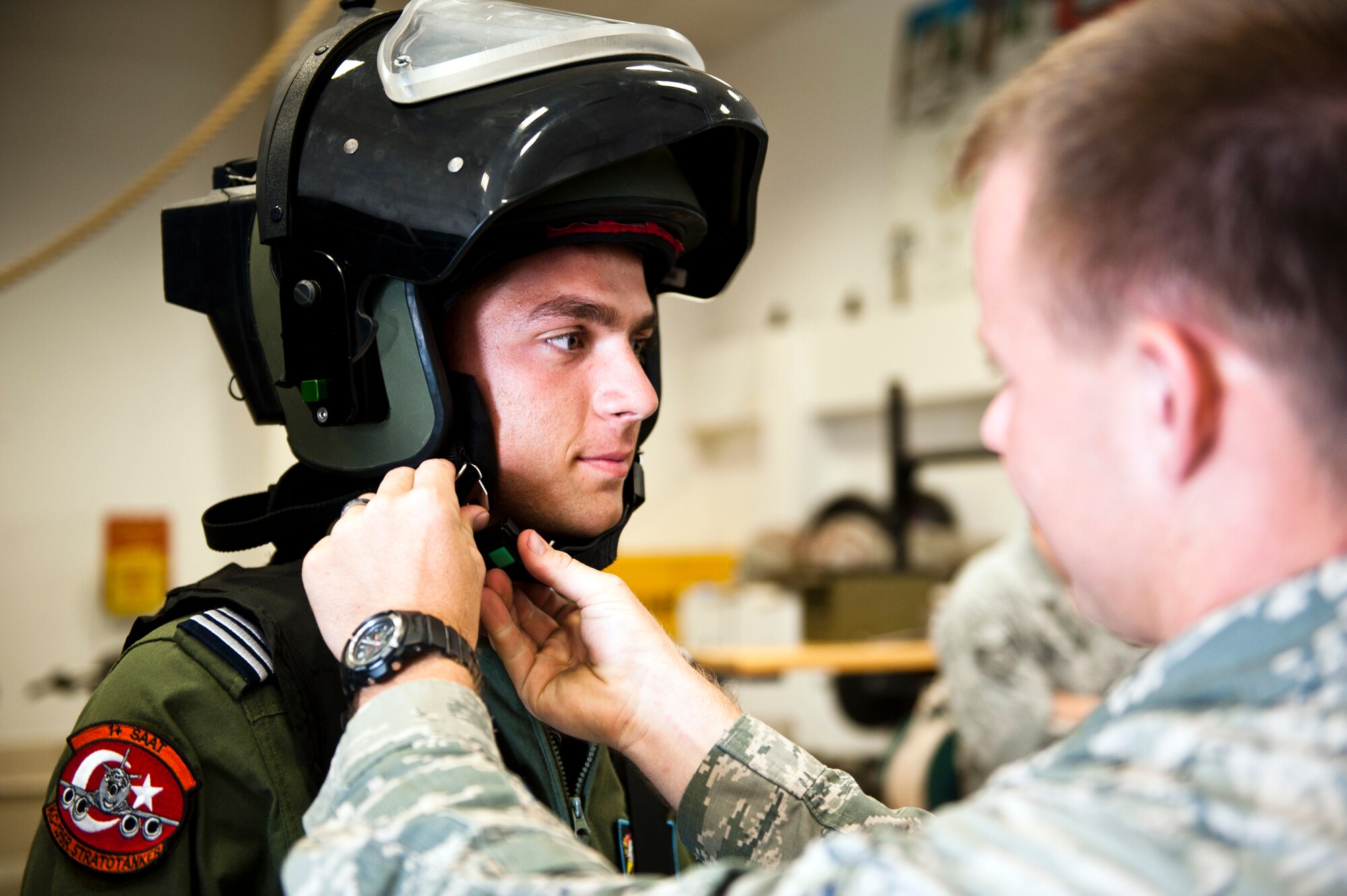Airman 1st Class Samuel Bassin, 39th Civil Engineer Squadron explosive ordnance disposal technician, helps a Turkish air force cadet put on a helmet for the EOD flight’s bomb suit July 15, 2013, at Incirlik Air Base, Turkey. During the base tour, the cadets were able to experience some of the EOD equipment first-hand. (U.S. Air Force photo by Senior Airman Daniel Phelps/Released)