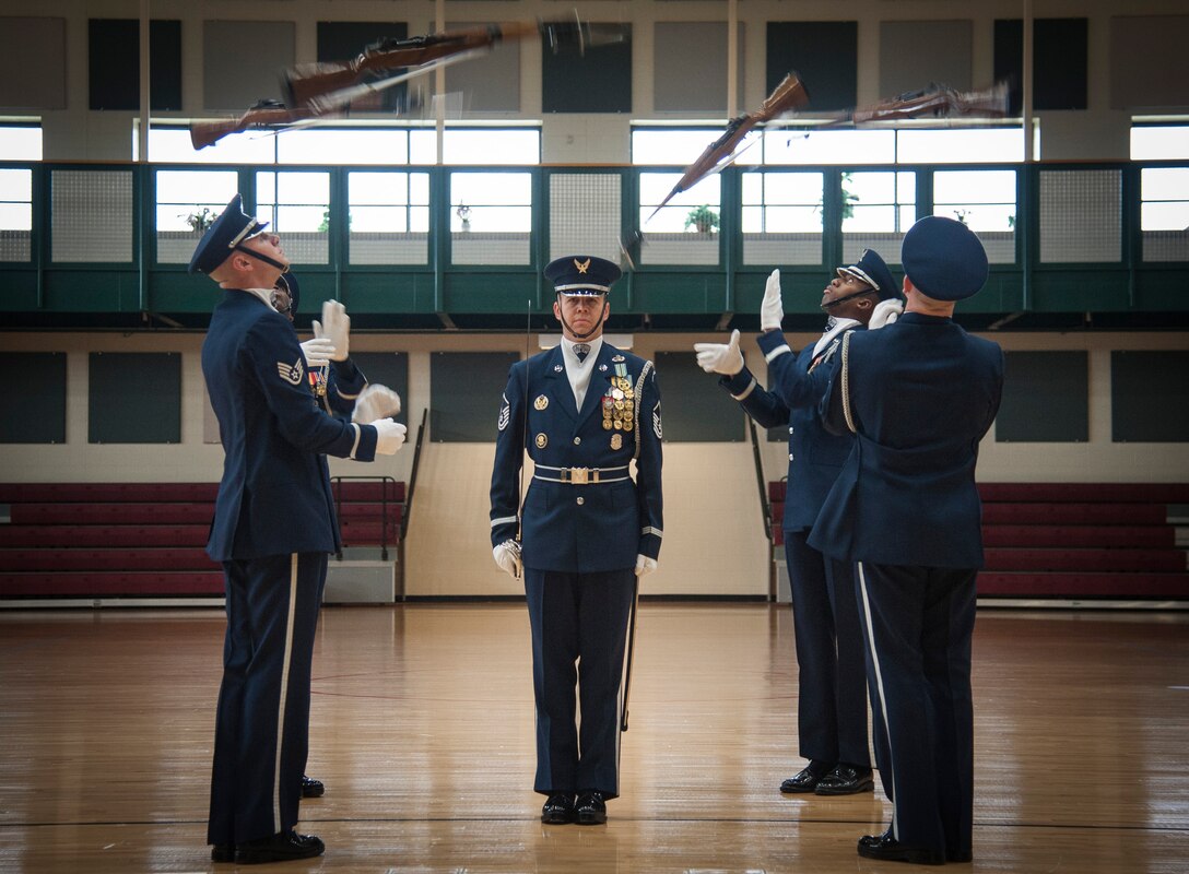 Four members of the U.S. Air Force Honor Guard drill team throw their rifles in the air as a fifth guardsman stands in the center during a performance at Laughlin Air Force Base, Texas, July 16, 2013. Twenty airmen make up the total drill team, and 250 ceremonial guardsmen comprise the entire U.S. Air Force Honor Guard. (U.S. Air Force photo/Senior Airman John D. Partlow)