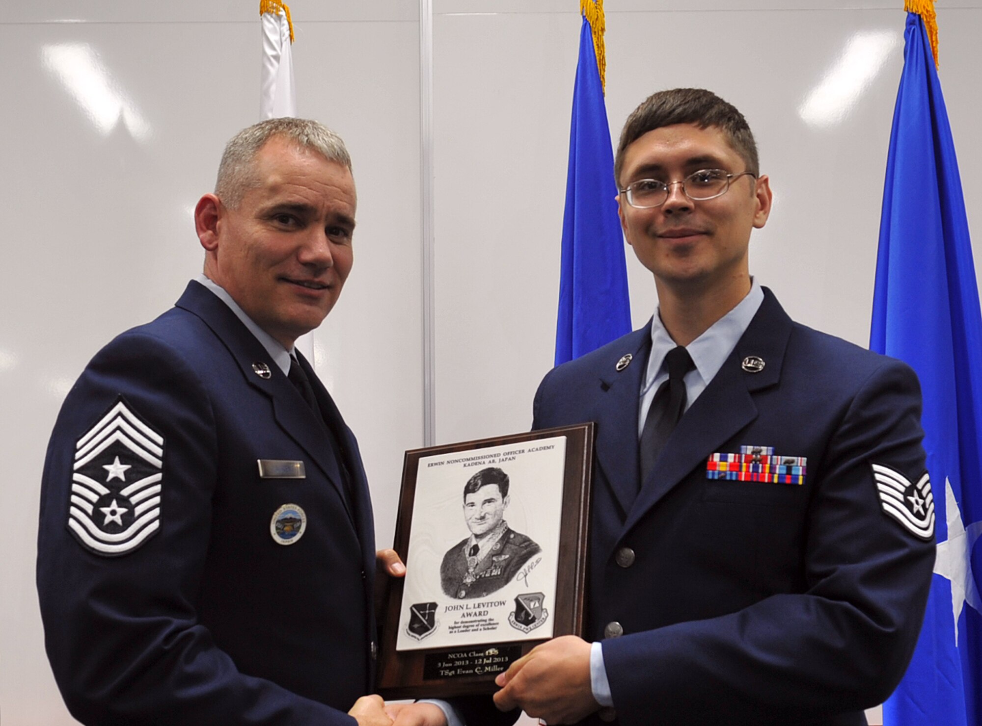 U.S. Air Force Chief Master Sgt. James Laurent, U.S. Forces Japan, and 5th Air Force command chief, presents Tech. Sgt. Evan Miller, Detachment 402, Air Force Technical Applications Center NCO in charge of maintenance operations at Yokota Air Base, Japan, the John L. Levitow award during the NCO Academy Class 13-5 graduation ceremony at the Erwin Professional Military Education Center on Kadena Air Base, Japan, July 12, 2013. This distinguished graduate award, named in memory of Medal of Honor recipient Airman 1st Class John L. Levitow, is presented to the most outstanding member of professional military education and denotes superior achievement as both a leader and a scholar. (U.S. Air Force photo by Naoto Anazawa/Released)