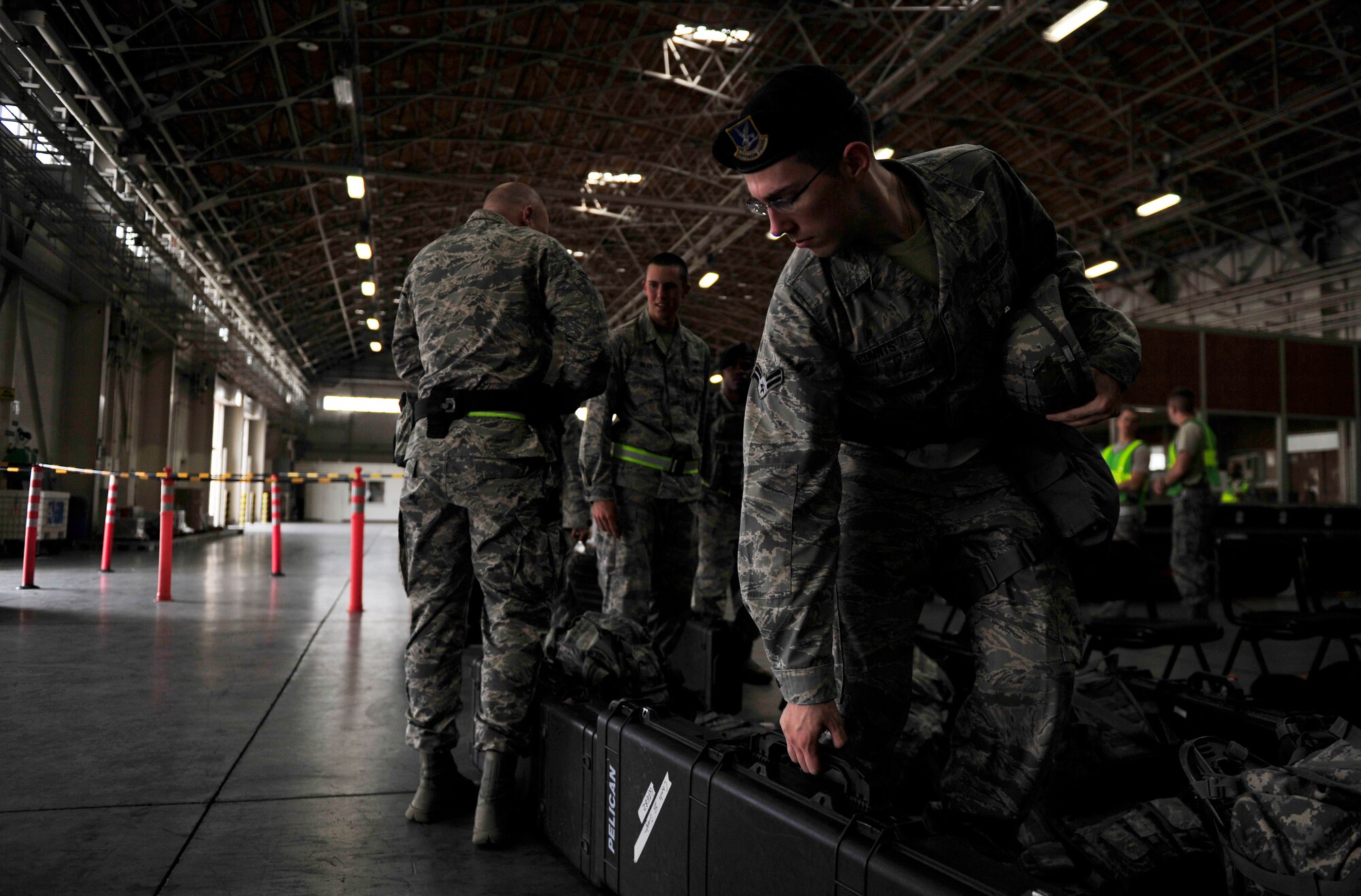 Airmen from the 374th Security Forces Squadron bring equipment and weapons into a building before receiving an exercise pre-deployment briefing and going through an exercise deployment line at Yokota Air Base, Japan, July 16, 2013. The briefing prepared Airmen of what to expect on their simulated deployment and the line allowed them to ask questions to and receive help from organizations from around base. Simulations such as this ensure the 374th Airlift Wing and Team Yokota is deployment ready in a moment's notice. (U.S. Air Force photo by Senior Airman Cody H. Ramirez)