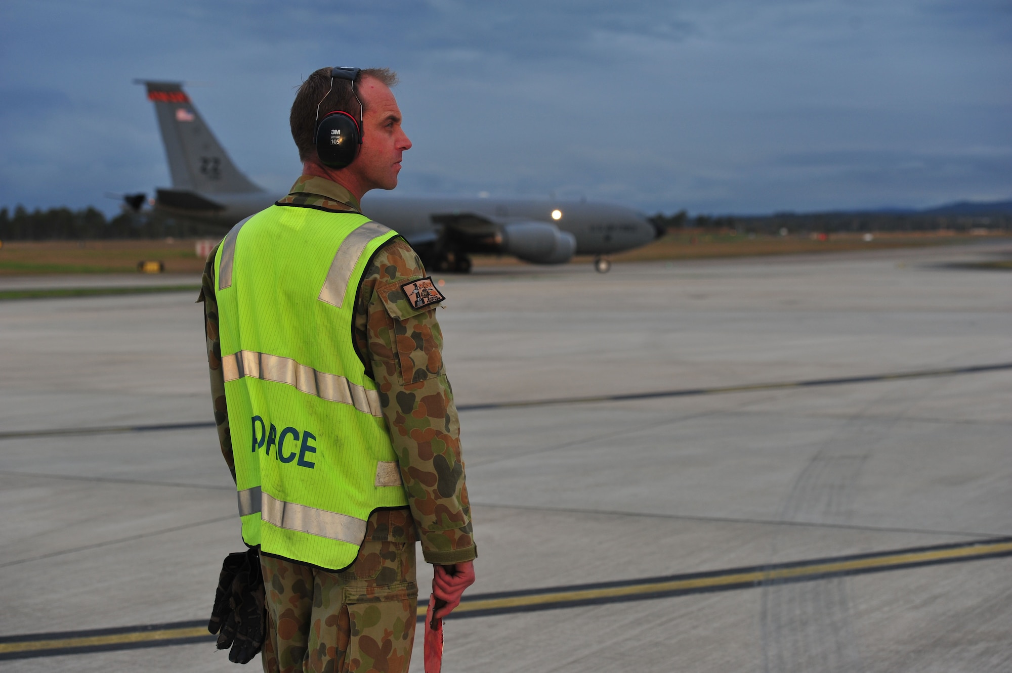 Royal Australian Air Force Leading Aircraftman Damien Deering, assigned to the No. 1 Airfield Operations Support Squadron, prepares to marshall a U.S. Air Force KC-135 Stratotanker from Kadena Air Base, Japan, to its parking space at Royal Australian Air Force Base Amberley, Australia, July 15, 2013. Two KC-135s arrived to provide aerial refueling during Talisman Saber 2013, a biennial training activity aimed at improving Australian Defence Force and U.S. combat readiness and interoperability as a combined joint task force. (U.S. Air Force photo by Staff Sgt. Rachelle Coleman/Released)