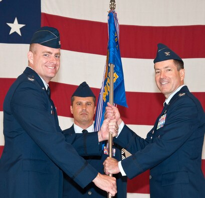 Col. David Chiesa, right, accepts the 71st Medical Group guidon from Col. Darren James, 71st Flying Training Wing commander, during the 71st MDG change of command ceremony held July 16 in Hangar 199 at Vance Air Force Base, Okla. In the background is Chief Master Sgt. Derek Madison, the 71st MDG superintendent. (U.S. Air Force photo/ Terry Wasson)