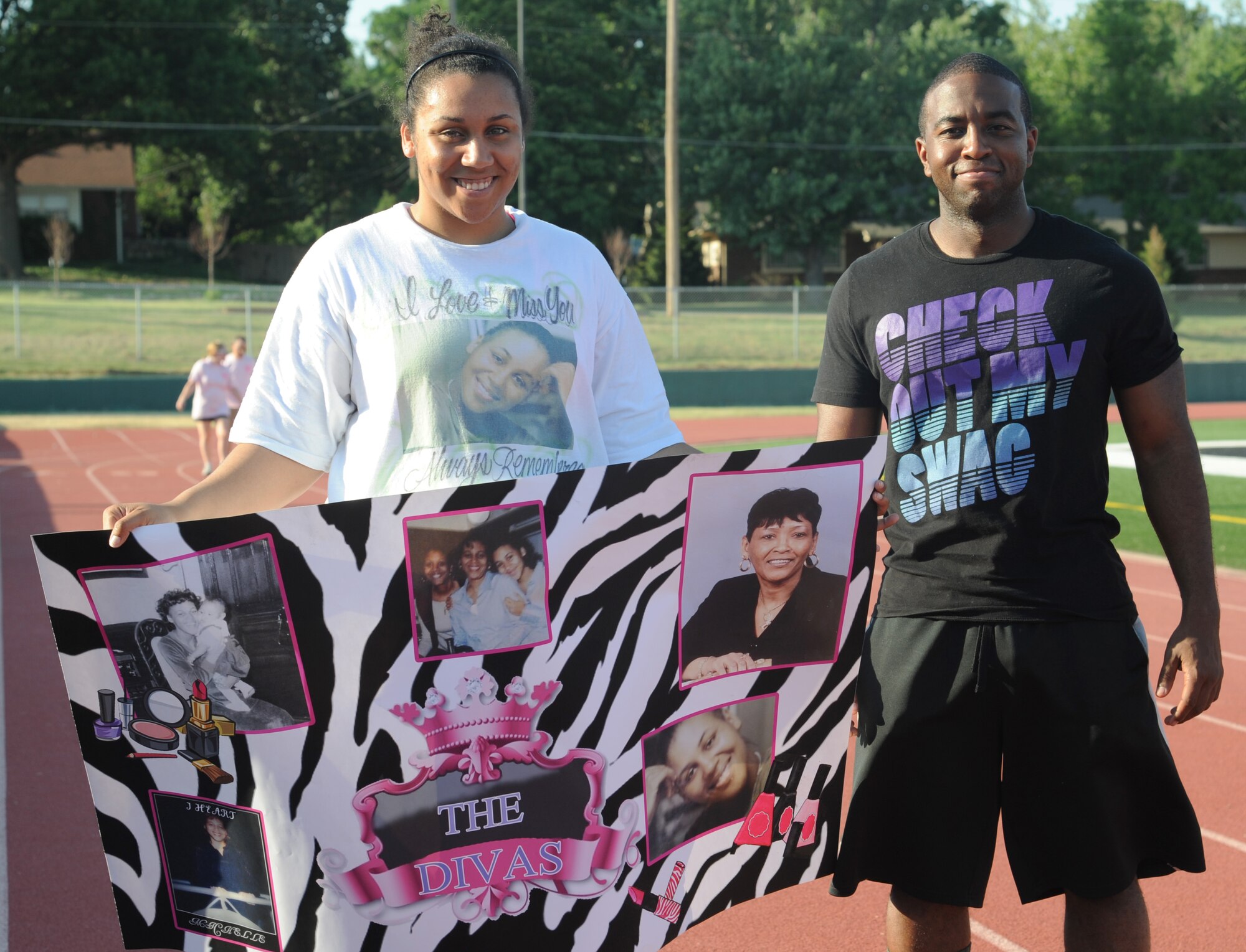 Senior Airman Roslyn Longmire, 384th Air Refueling Squadron boom operator, holds a poster alongside Airman 1st Class Matthew Hammond, 22nd Contracting Squadron contracting administrator, in remembrance of her mother and aunt who have lost their lives to cancer at the Relay for Life of Derby July 12, 2013, Derby Kan. RFL is an overnight fundraiser where participants honor the lives of people who fought cancer. (U.S. Air Force photo/Airman 1st Class John Linzmeier)