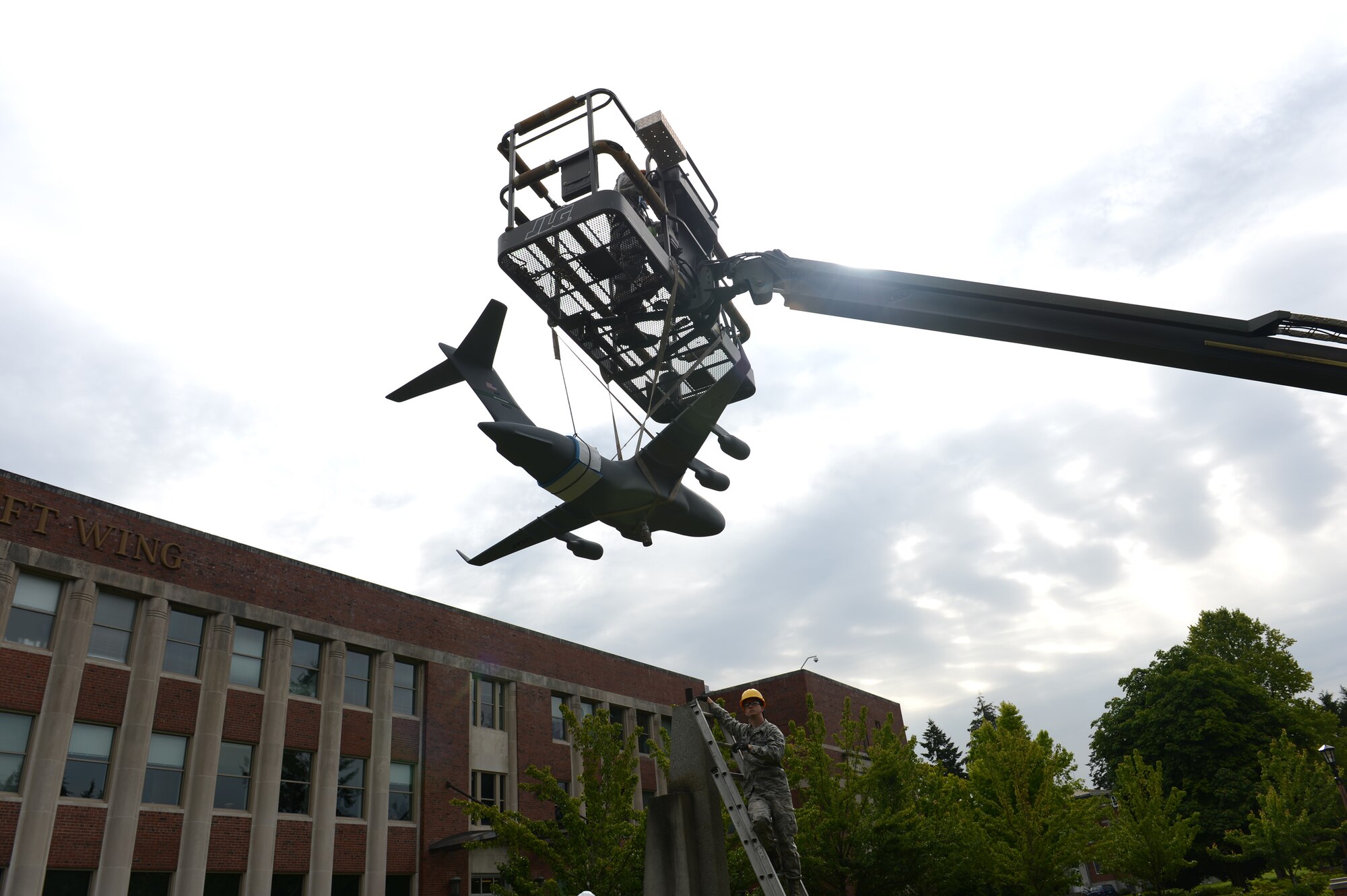 Members from the 627th Civil Engineering Squadron replace a model C-17 Globemaster III aircraft, July 12, 2013, on its pedestal outside the 62nd Airlift Wing headquarters building at Joint Base Lewis-McChord, Wash. The model was replaced after being restored by Airman 1st Class Justin Lounder, 62nd Maintenance Squadron structural maintenance technician. (U.S. Air Force photo/Airman 1st Class Jacob Jimenez)