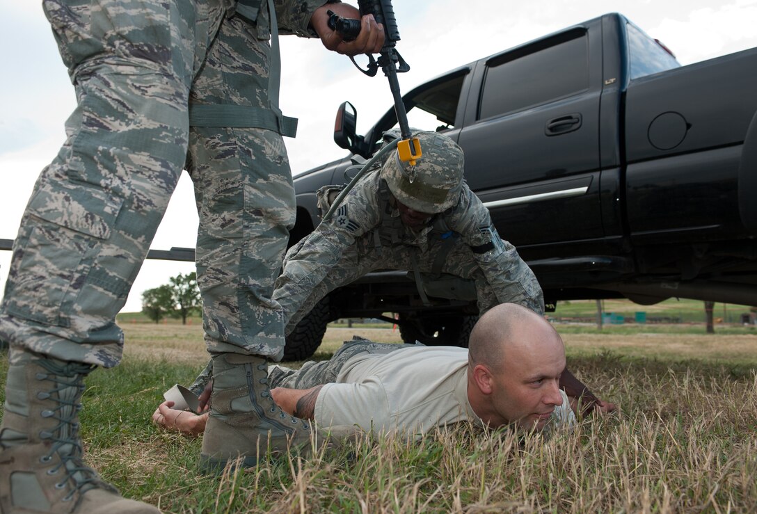 Senior Airman Travis Robertson, 28th Civil Engineer Squadron heating, ventilation and air conditioning technician, apprehends Master Sgt. Christopher Moffett, base Exercise Evaluation Team member, for a simulated security check at an entry control point during the Phase II portion of an operational readiness exercise at Ellsworth Air Force Base, S.D., July 11, 2013. During the Phase II segment of the ORE, EET members put Airmen to the test by creating scenarios and observed how the Airmen reacted and responded to problems. (U.S. Air Force photo by Airman 1st Class Alystria Maurer/Released)