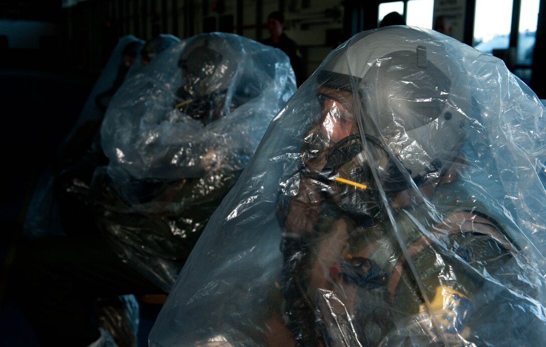 Airmen from the 37th Bomb Squadron sit in plastic sheets prior to decontamination during the Phase II portion of an operational readiness exercise at Ellsworth Air Force Base, S.D., July 10, 2013. The bags are one of several stations requiring Airmen to remove articles of gear and clothing to safely decontaminate themselves and to prevent further contamination of harmful chemicals to the area. (U.S. Air Force photo by Airman 1st Class Rebecca Imwalle/Released)