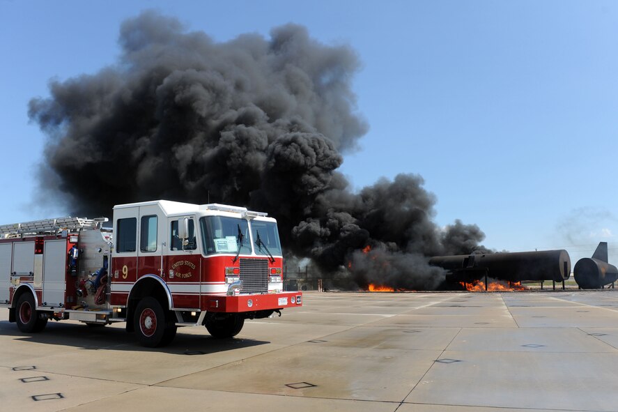 Airmen assigned to the 28th Civil Engineer Squadron Fire Department circle a simulated aircraft fire during the Phase II portion of an operational readiness exercise on Ellsworth Air Force Base, S.D., July 10, 2013. The ORE was designed to provide Airmen education, exposure and experience with Phase II operations which includes simulated attacks in a deployed location. (U.S. Air Force photo by Airman 1st Class Rebecca Imwalle/Released)