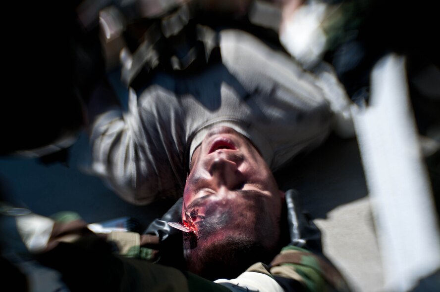 Airmen assigned to the 28th Aircraft Maintenance Squadron treat Senior Airman Gary Jarvis, 28th AMXS crew chief, with simulated self-aid and buddy care on the flightline during the Phase II portion of an operational readiness exercise at Ellsworth Air Force Base, S.D., July 11, 2013. OREs are designed to prepare and train Airmen for real-world contingencies in a deployed environment. (U.S. Air Force photo by Airman 1st Class Zachary Hada/Released)