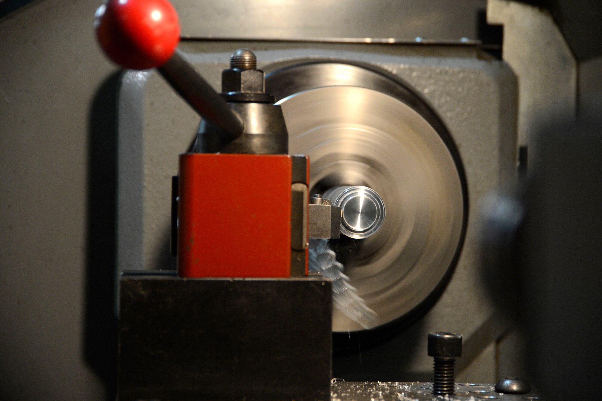 The HAAS  Computer Numerical Control Toolroom Lathe 1 cuts metal off a piece of stock to create a hydraulic bleeder brake here, July 11, 2013. The CNC TL-1 features a proprietary conversational operating system that makes cutting parts and creating part programs nearly effortless. The operator chooses an operation, touches off the X and Z surfaces and is then prompted to enter basic dimension information. (U.S. Air Force photo by Master Sgt. Christopher A. Campbell)
