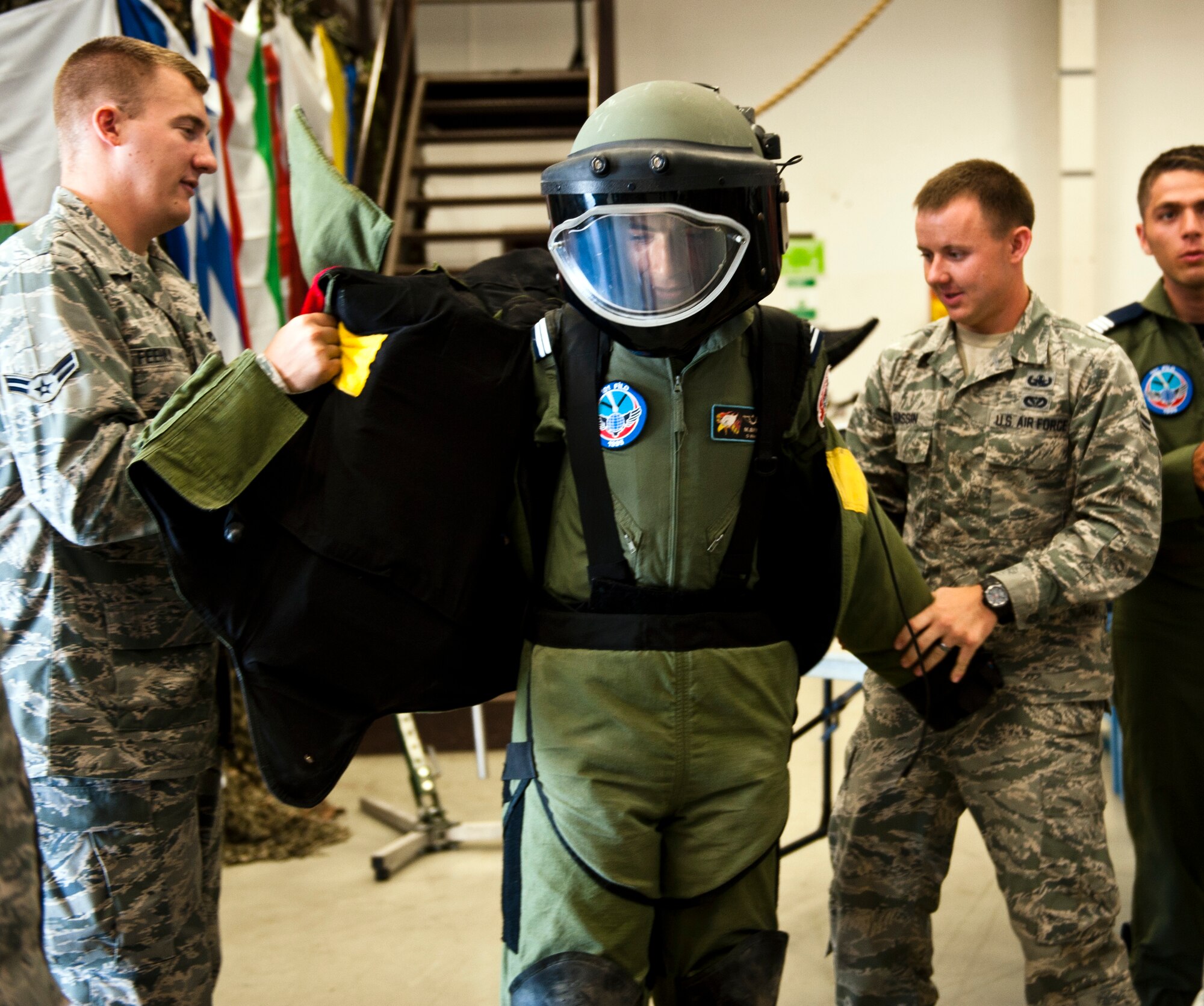 Airman 1st Class Daniel Feehily and Airman 1st Class Samuel Bassin, 39th Civil Engineer Squadron explosive ordnance disposal technicians, help a Turkish air force cadet put on a bomb suit July 15, 2013, at Incirlik Air Base, Turkey. The cadet tour provided U.S. Airmen the opportunity to demonstrate the U.S. military’s professional enlisted corps. (U.S. Air Force photo by Senior Airman Daniel Phelps/Released)